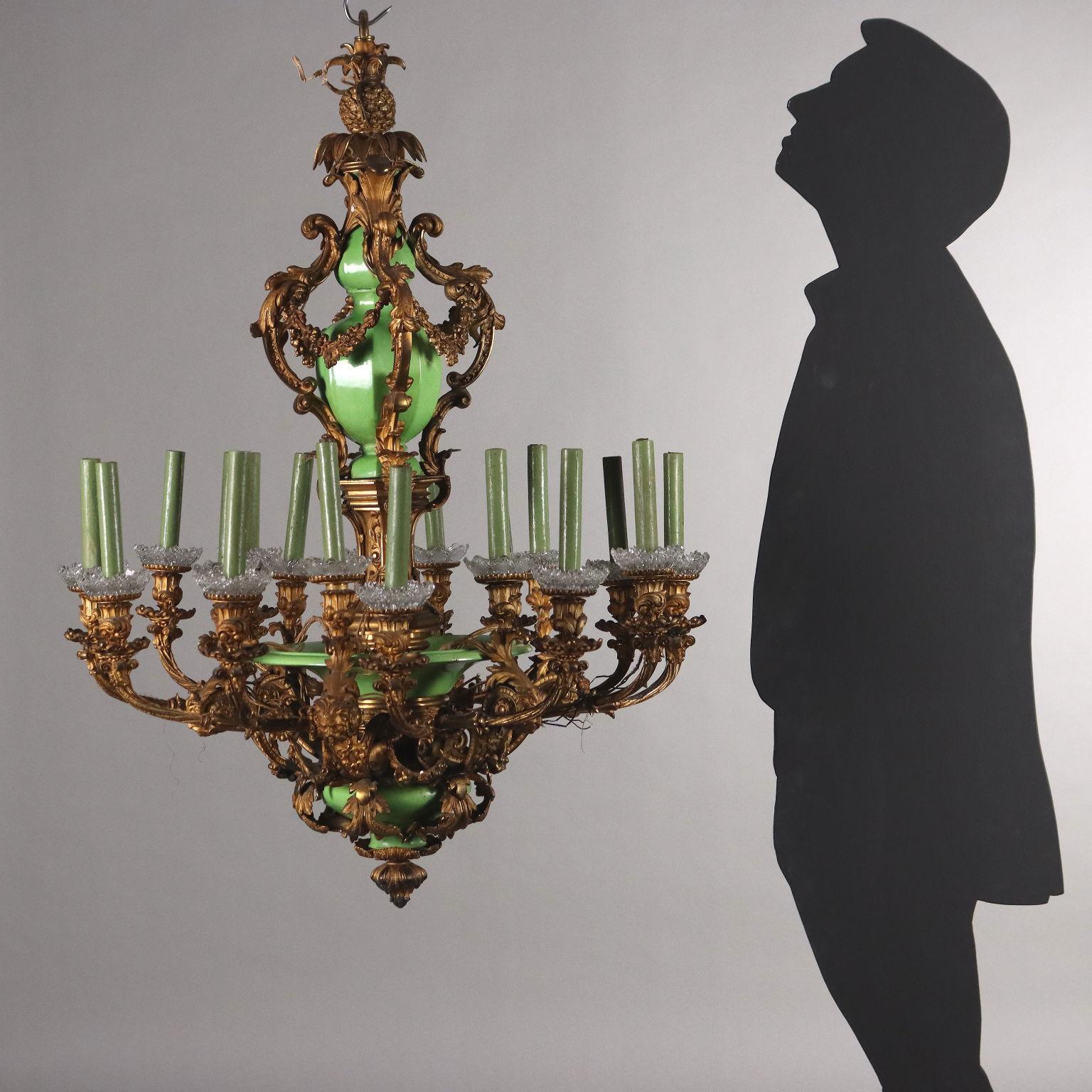 Lampadario Napoleone III a diciotto luci disposte su doppio ordine, Francia terzo quarto XIX secolo. Struttura in bronzo dorato, contraddistinta nel fusto centrale dalla presenza di parti in ceramica invetriata verde; il bronzo dorato è