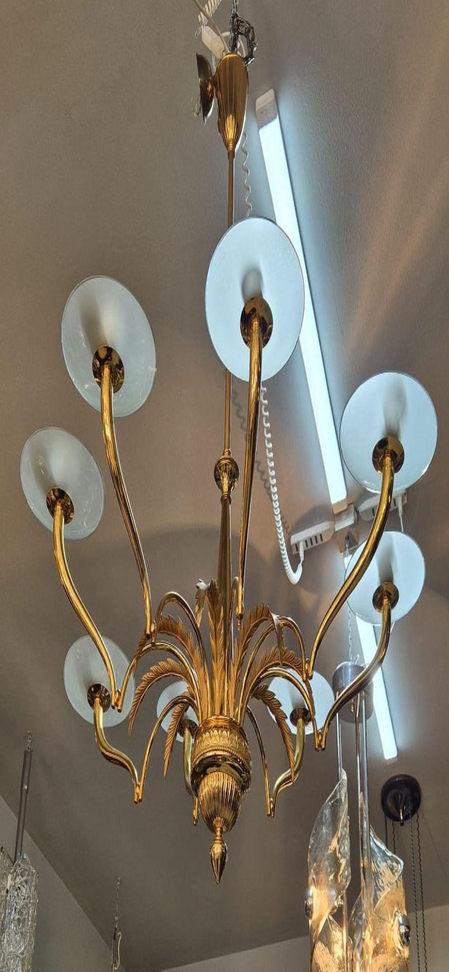 Gold eight-light chandelier designer Oscar Torlasco for Lumi Milano. The metal frame features eight arms with glass lampshades and metal leaves between each arm.