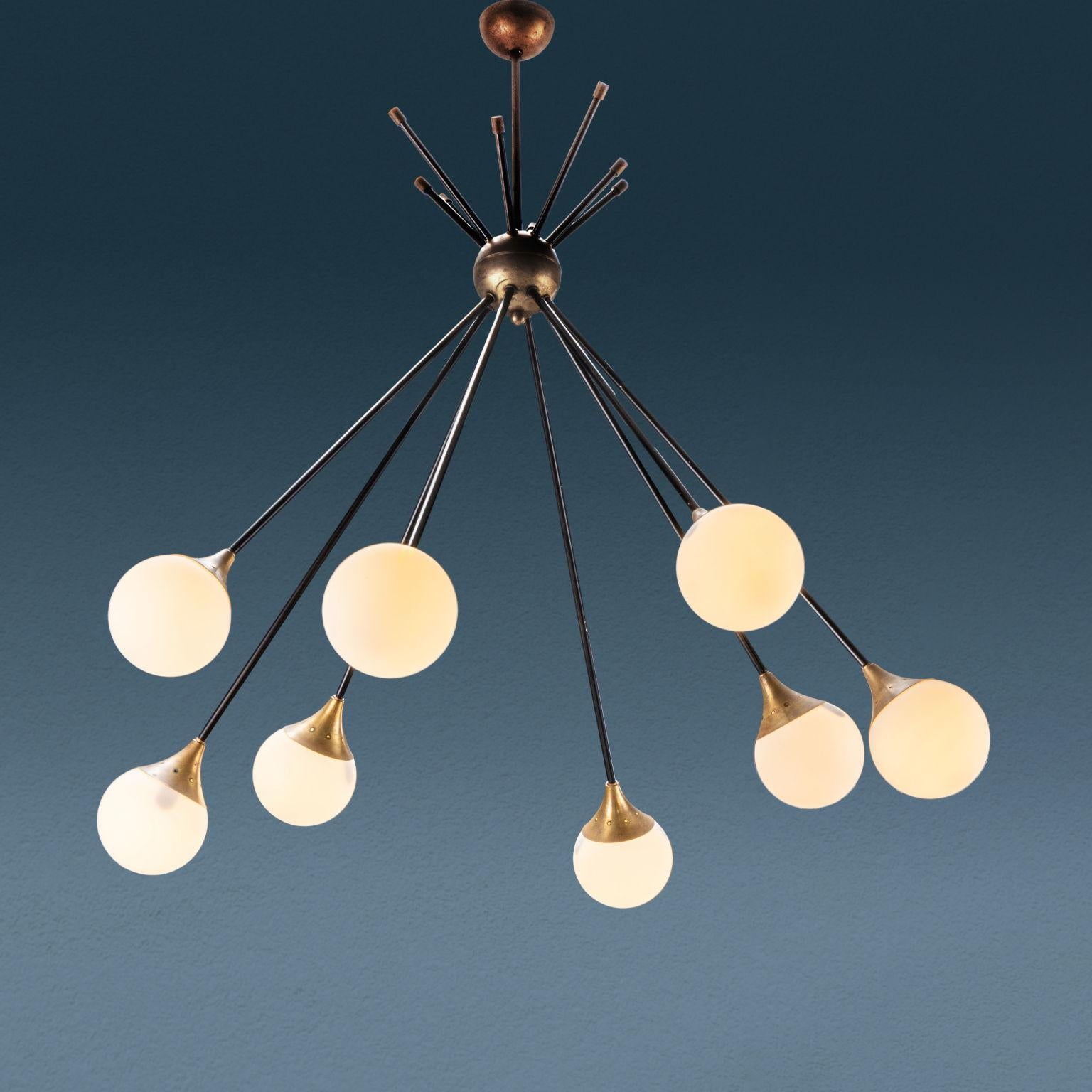 Raffinato lampadario realizzato negli anni '50 '60 ad otto punti luce con struttura tipo sputnik in ottone e paralumi in vetro opalino.
Di manifattura italiana, ricorda le eleganti produzioni Stilnovo.