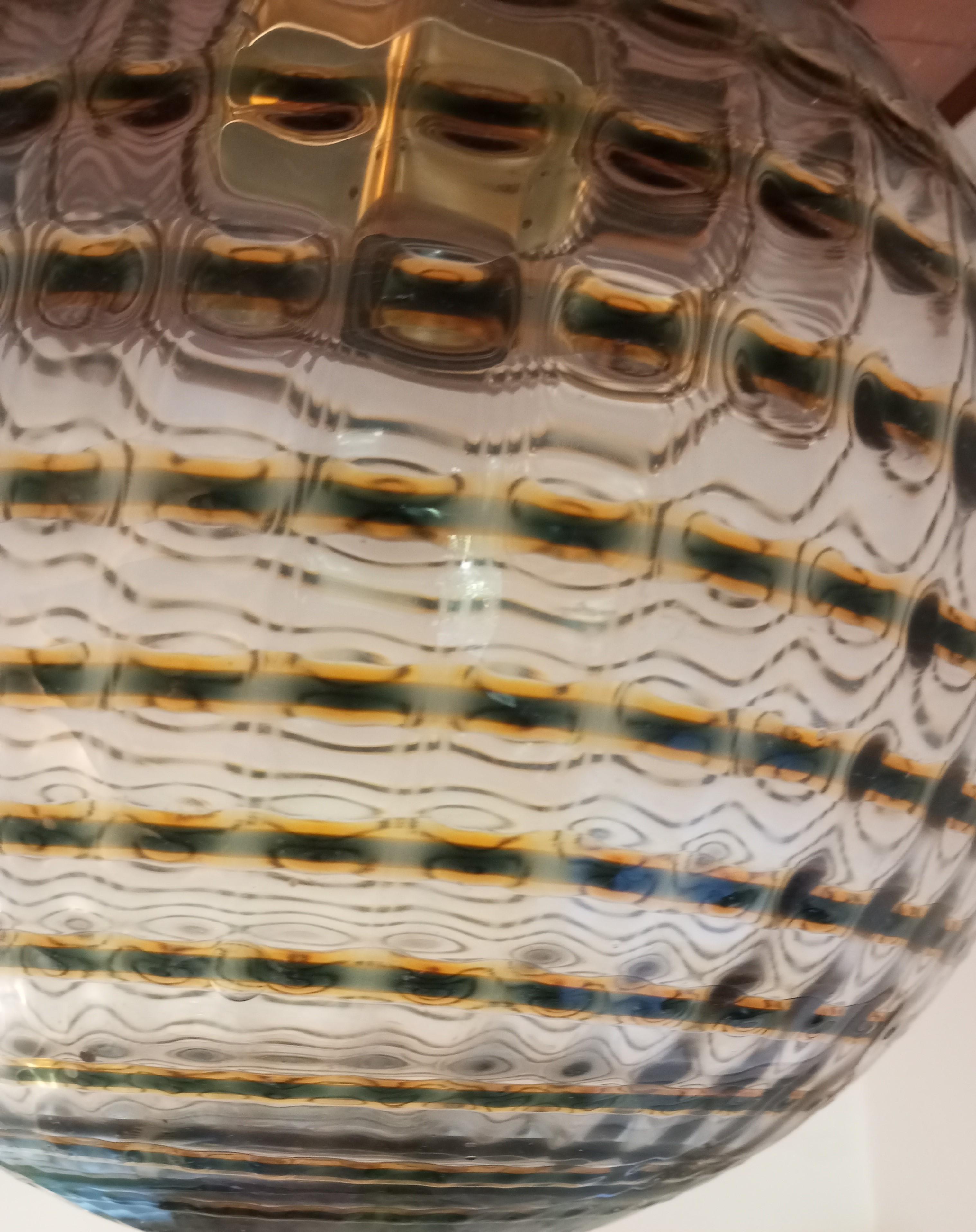 Lampada a sospensione tonda con vetro di Murano, anni ’60. Attribuita al designer Ludovico Diaz de Santillana direttore dell’azienda Venini. Con vetro trasparente e vetro artistico colorato nei toni del marrone, e con maestria degli artigiani si