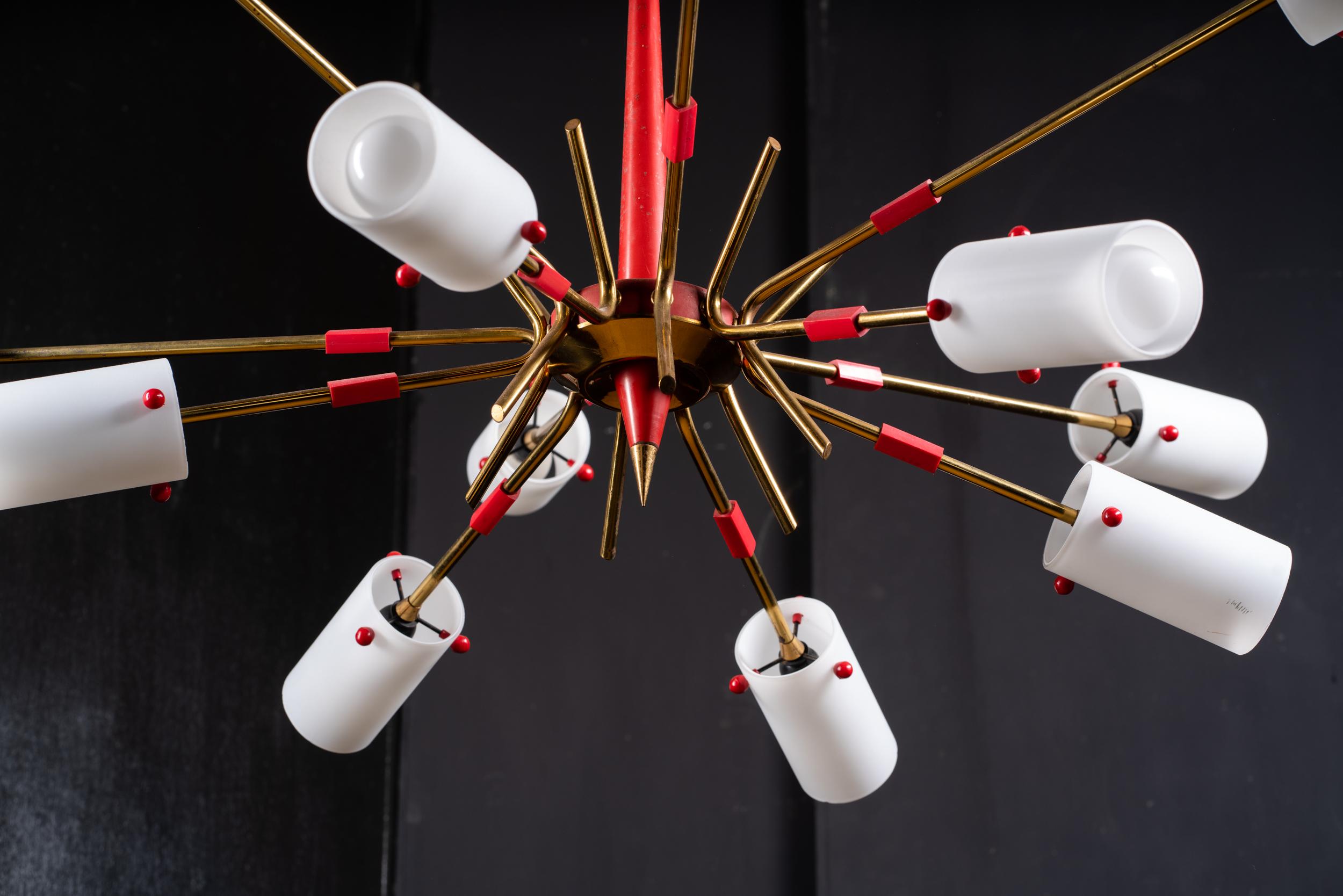 Prominent 12-arm Sputnik chandelier made of red lacquered metal, brass, and white blown glass.
Designed and produced in Italy in the 1950s, in the style of Stilnovo 