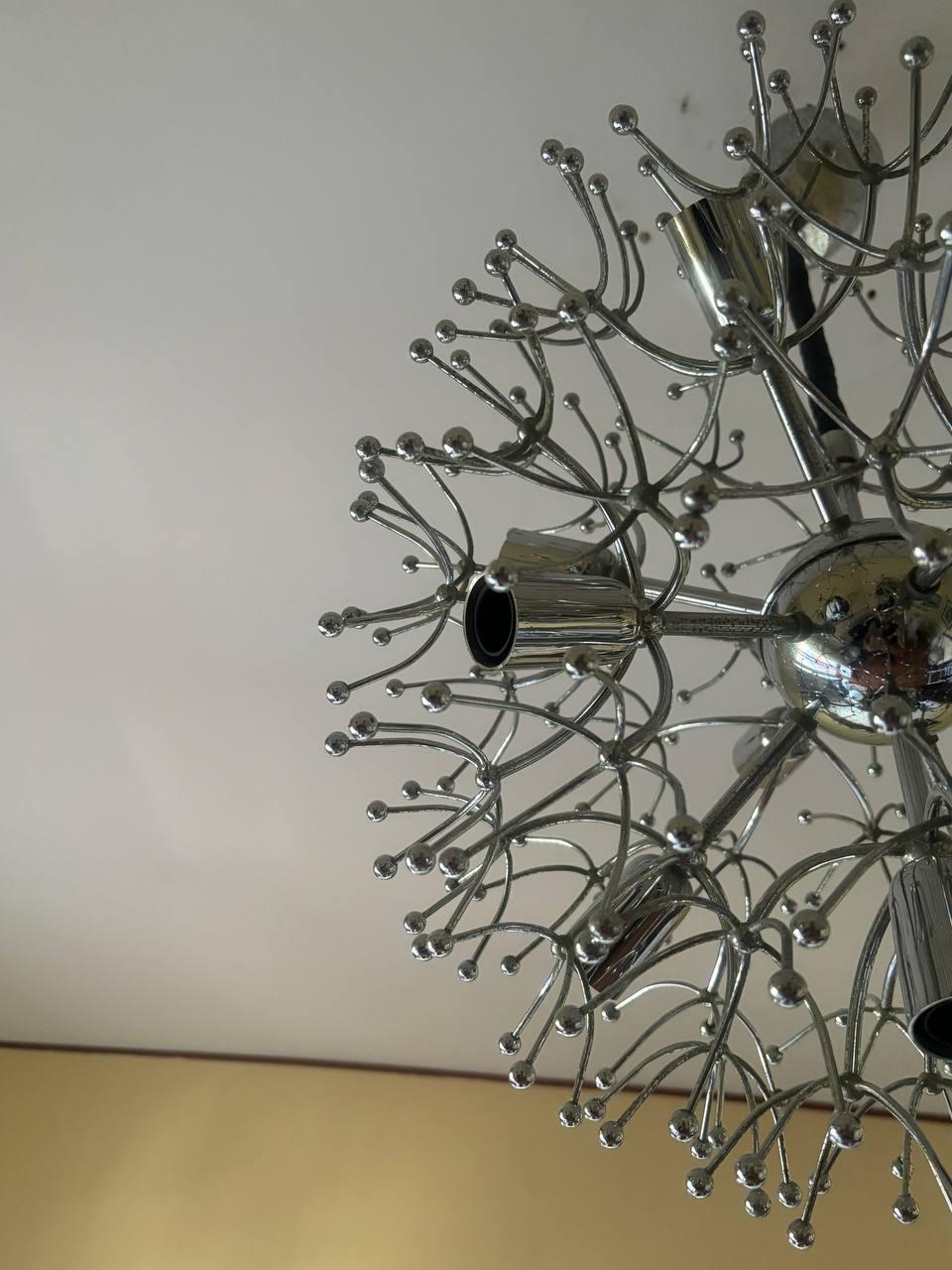 Lámpara de techo Sputnik de Gaetano Sciolari - años 70.
El llamativo diseño de esta lámpara de techo consiste en delicadas hojas cromadas que irradian desde el núcleo central. La disposición recuerda a las plumosas semillas de un diente de león al