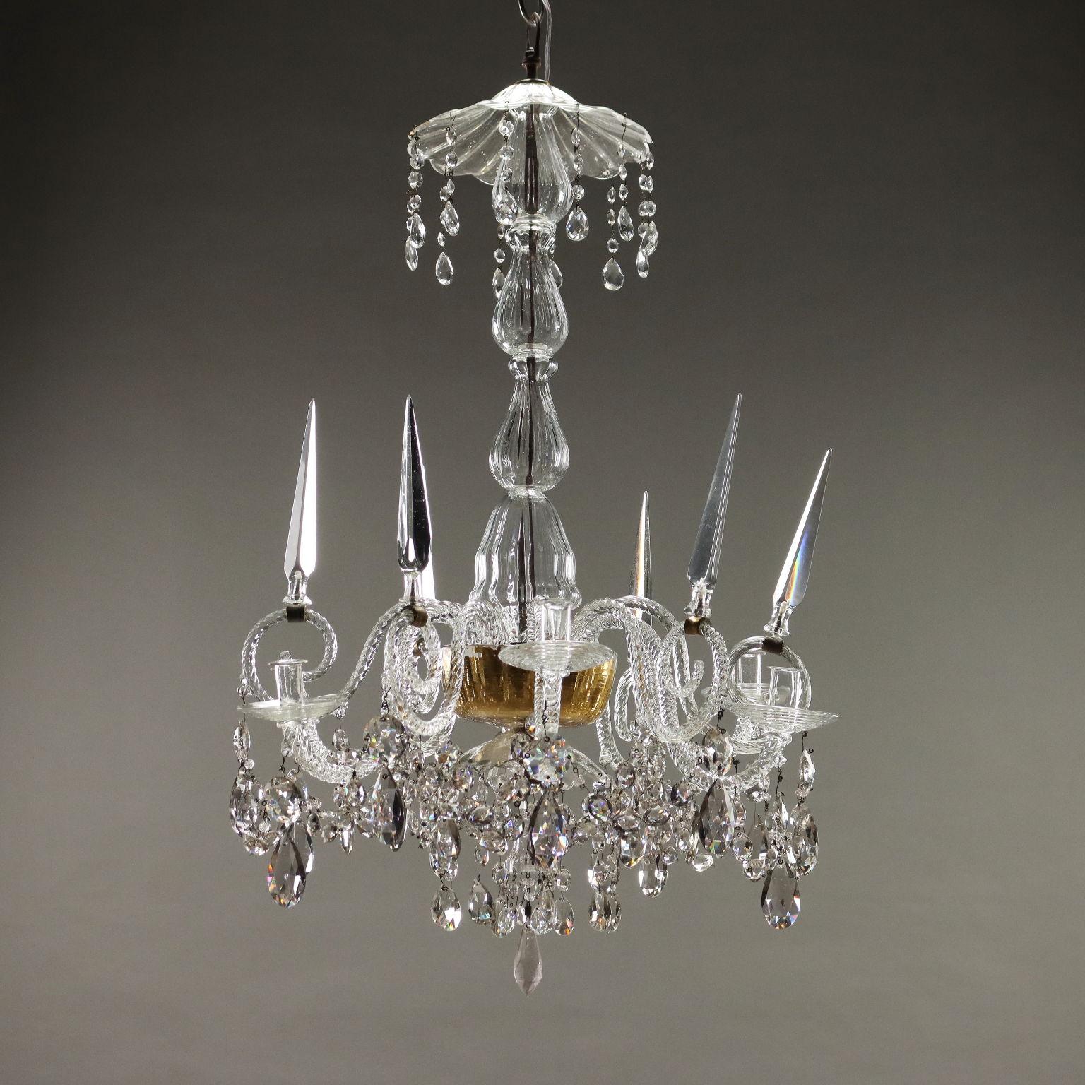 Lampadario Veneziano in vetro soffiato trasparente, sei luci collocate su braccia mosse alternate a sei puntali su braccia a ricciolo. Piatto centrale dorato internamente a foglia d'oro, pendenti e collane in vetro. Da elettrificare perché il