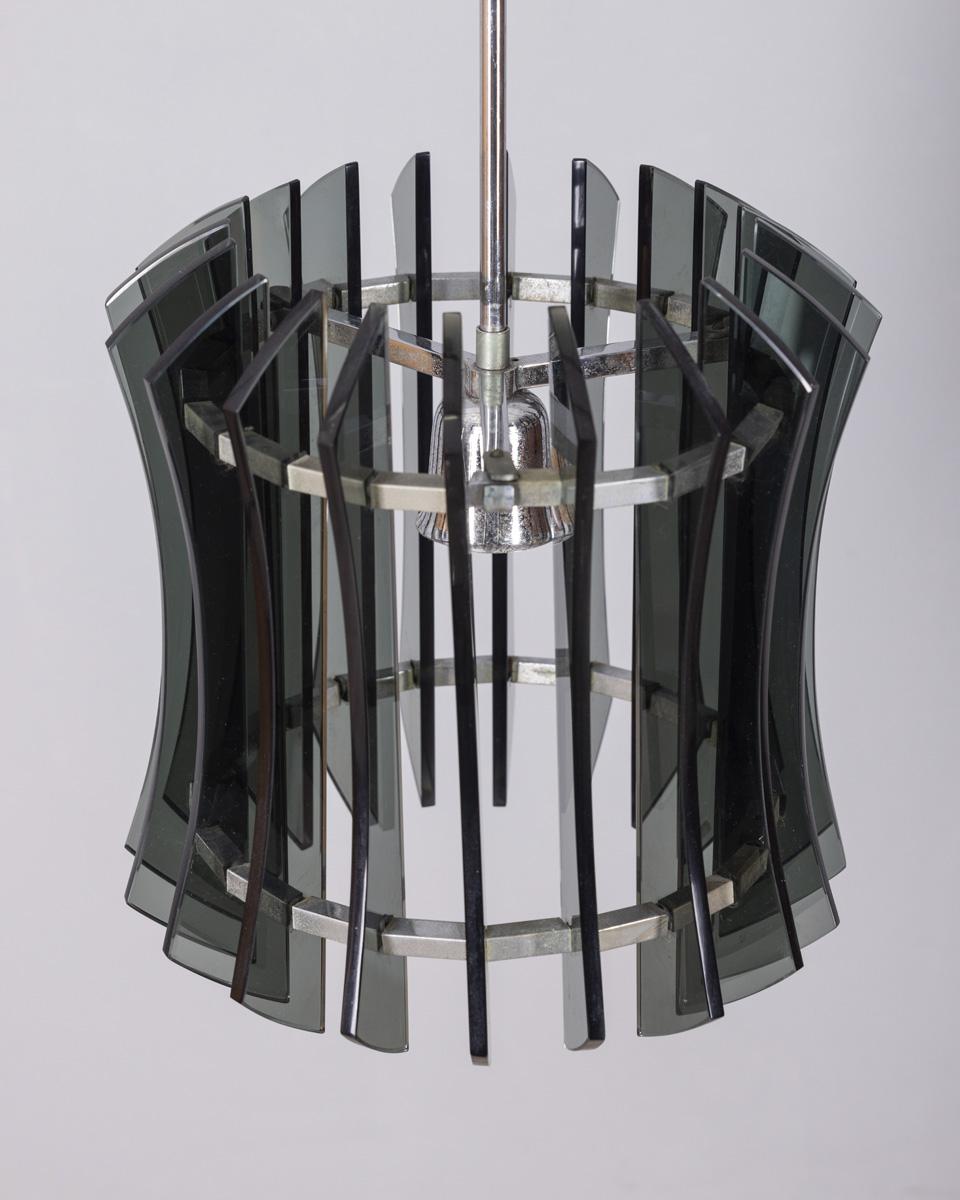 Lampadario a strisce di vetro cromato e metallo fumè, design VECA, anni '60.

CONDIZIONE:
In buone condizioni, funzionante, può presentare segni di usura dovuti all'età.

DIMENSIONI:
Altezza 95 cm; Diametro 30 cm.

MATERIALI:
Metallo e vetro.

ANNO