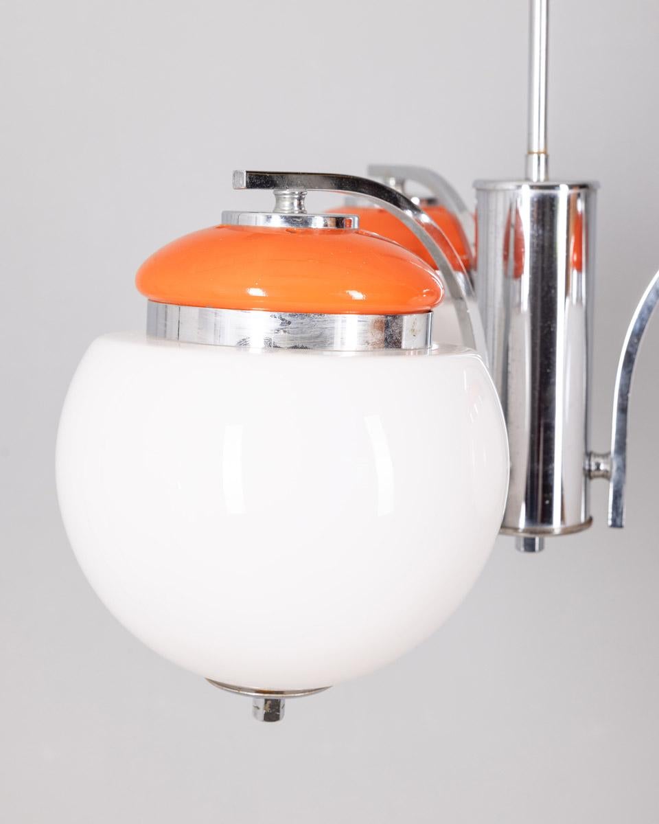 Lampadario con struttura in metallo cromato e arancione, a tre paralumi in vetro bianco, design italiano, anni 70.

CONDIZIONI:
In buone condizioni, funzionante, può presentare segni d'usura dati dal tempo.

DIMENSIONI: 
Altezza 82 cm; Diametro 50
