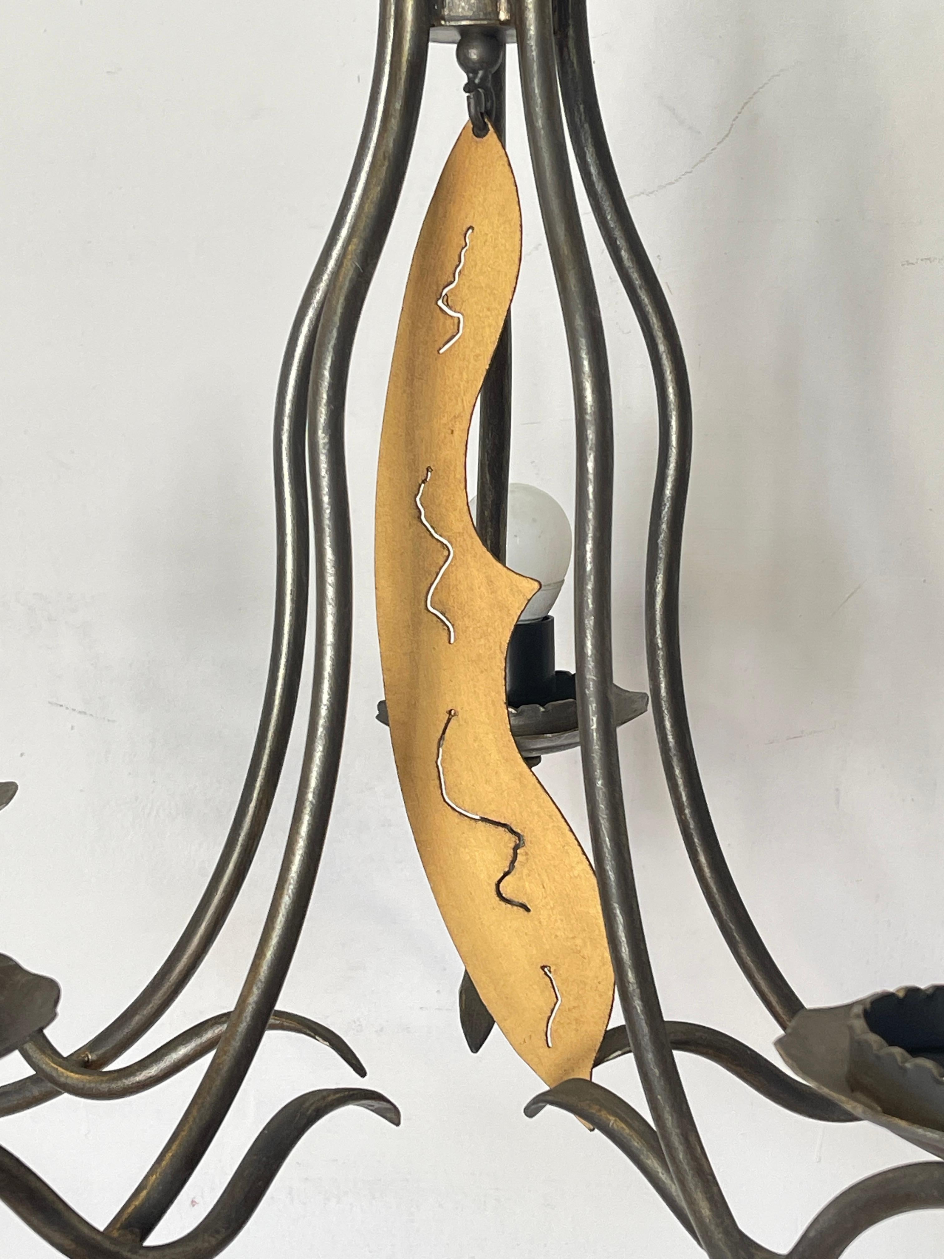 Bring a touch of rustic elegance and authentic craftsmanship to your home with this vintage wrought-iron chandelier, decorated with a hand-shaped wooden center pendant and corrugated metal details that echo the floral style.

With its 5 lights