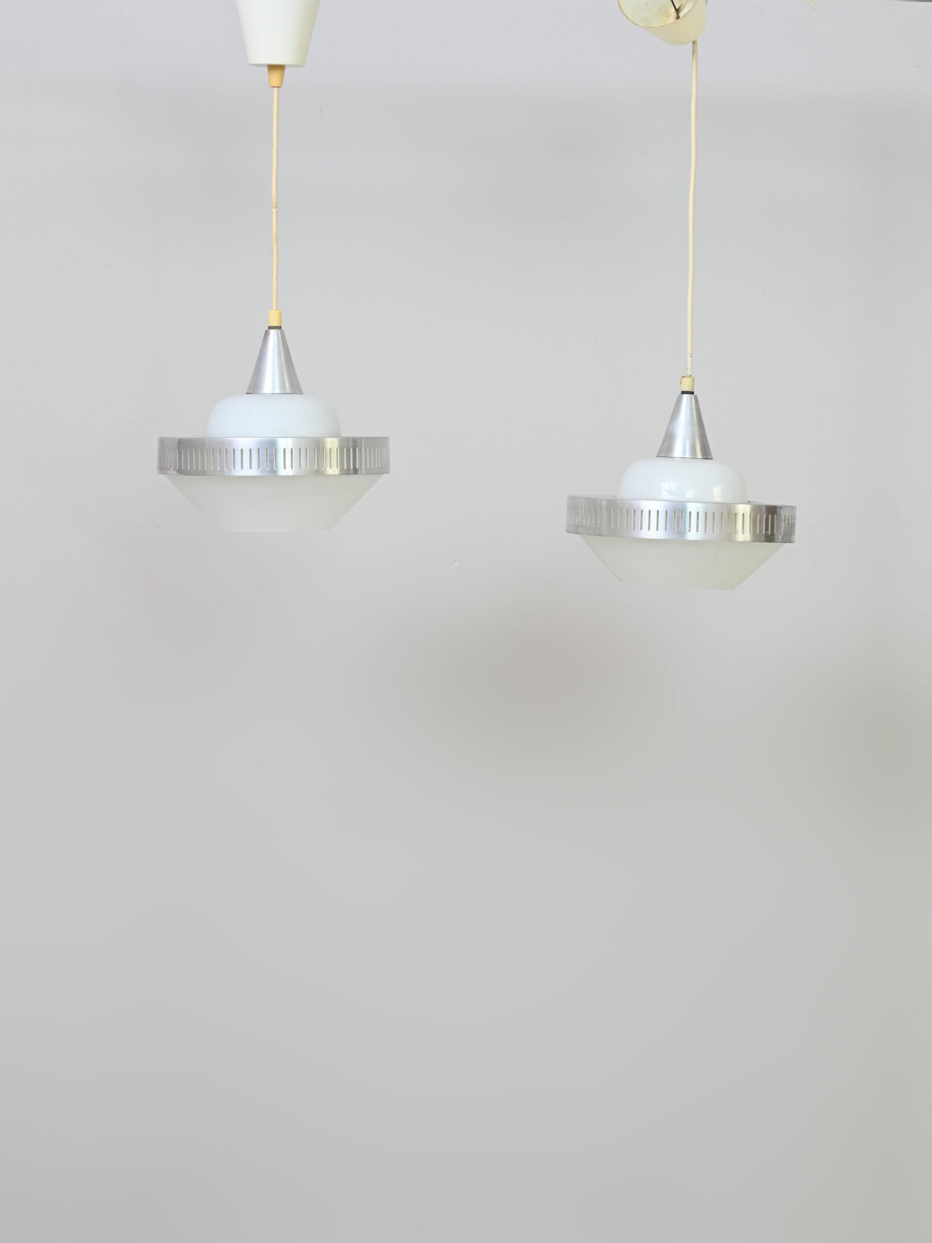 Coppia di lampade vintage originali anni ‘60

Il paralume è in vetro opalino e presenta dei dettagli in lamiera lavorata.
Creano una luce soffusa e direzionata verso il basso. Ideali sopra il tavolo da pranzo, in sala o in cucina.

Questa lampade
