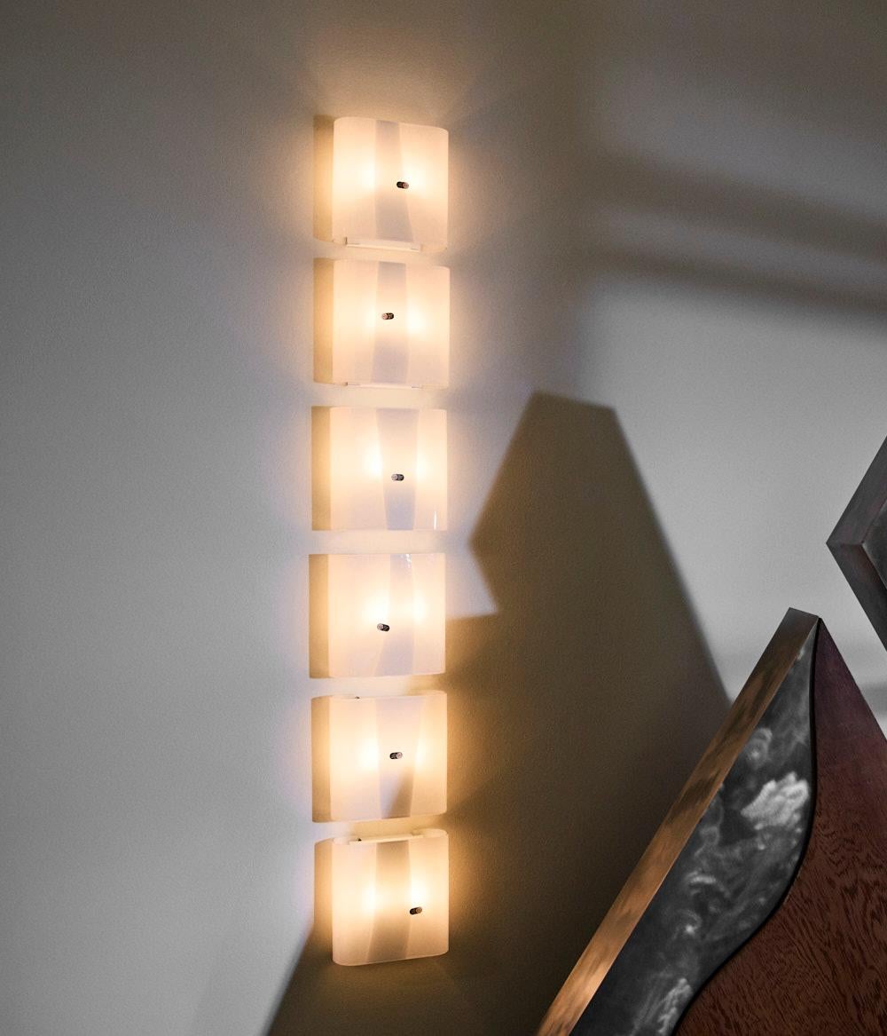 Lampade da parete mod. LP 259 in vetro di Murano semitrasparente con fascia bianca, disegnate da Carlo Nason per A.V. Mazzega nel 1970 ca. Si tratta di lampade provenienti da un fondo di magazzino e quindi in condizioni pari al nuovo.
Carlo Nason