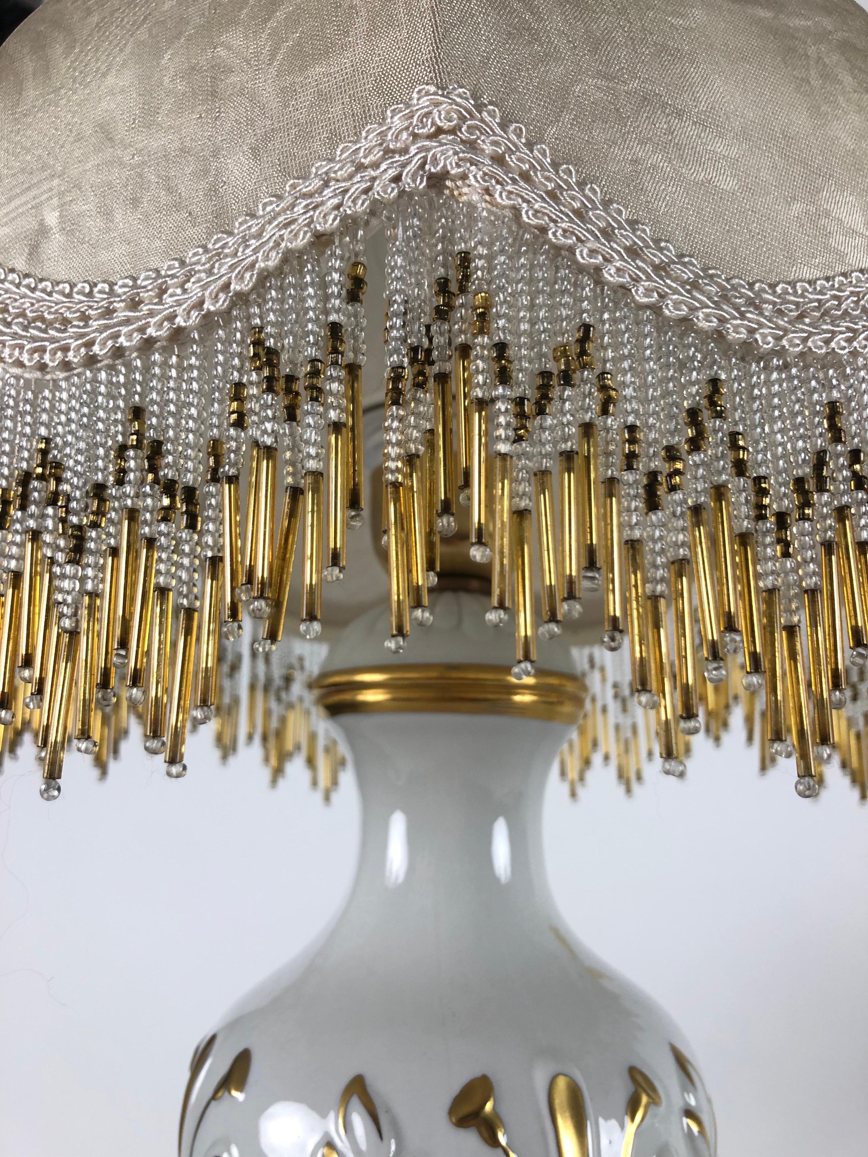 Lampade Da Tavolo Porcellana Bianca Dipinta in Oro con motivi floreali in rilievo.  De forme circulaire, il s'agit d'une production artisanale fiorentine qui remonte aux années Forma. Elle est réalisée à la main en or fin avec des motifs et des