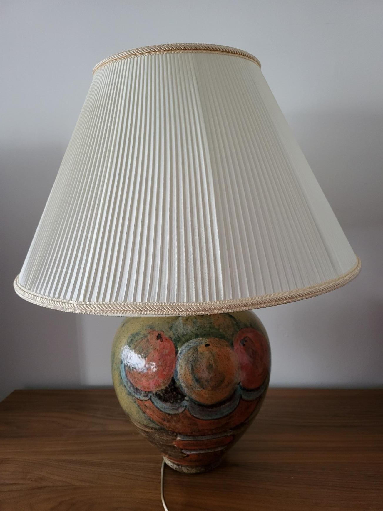 Découvrez cette magnifique lampe en céramique française, un véritable bijou de décoration pour votre intérieur. Présentée dans un superbe état, cette lampe Hubert Olivier est ornée d'un charmant décor de fruits aux couleurs chaudes de l'automne,