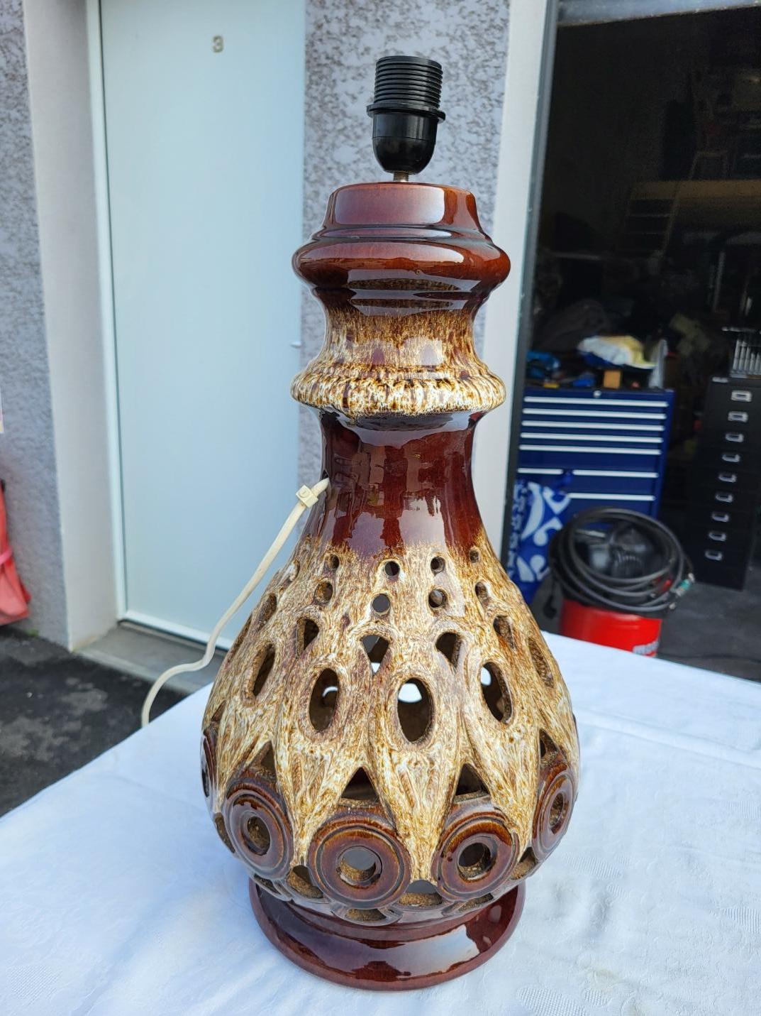Scopri questa lampada West Germany a doppia illuminazione, che si distingue per la sua grande altezza di 60 cm. Realizzata in céramique vintage, vanta un design ajouré e un finale brillante ed eclatante. Ideale per creare un'atmosfera rétro chic