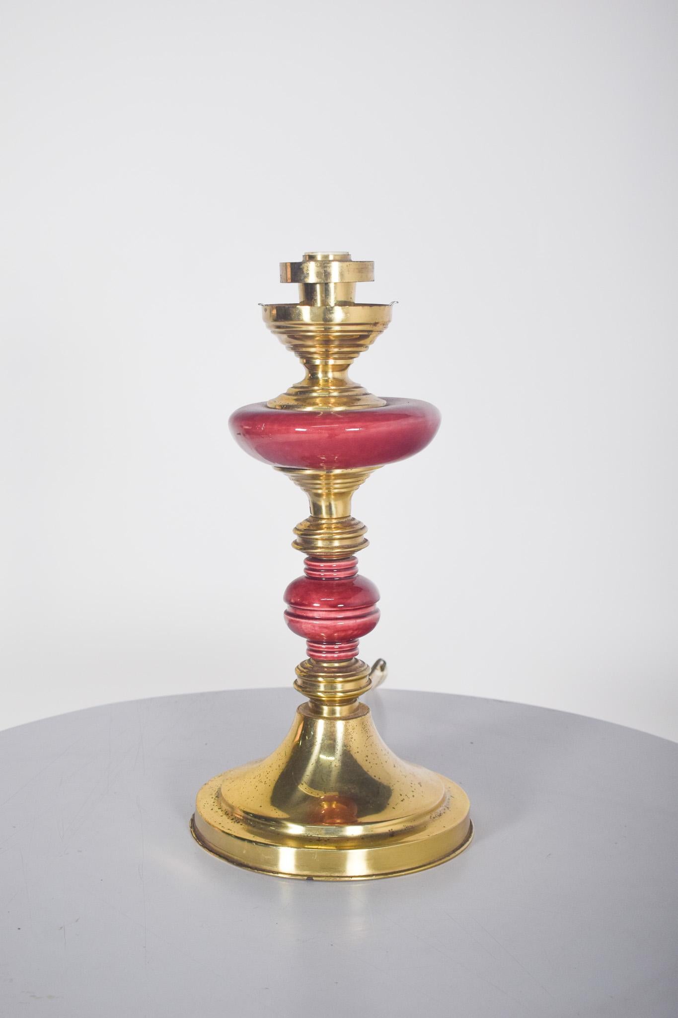 Abat-jour en métal jaune et porcelaine rouge. Avec une structure en métal doré et d'élégants détails en porcelaine rouge. La base large et arrondie donne de la stabilité à la pièce, tandis que le corps est composé d'éléments tournés, alternant des