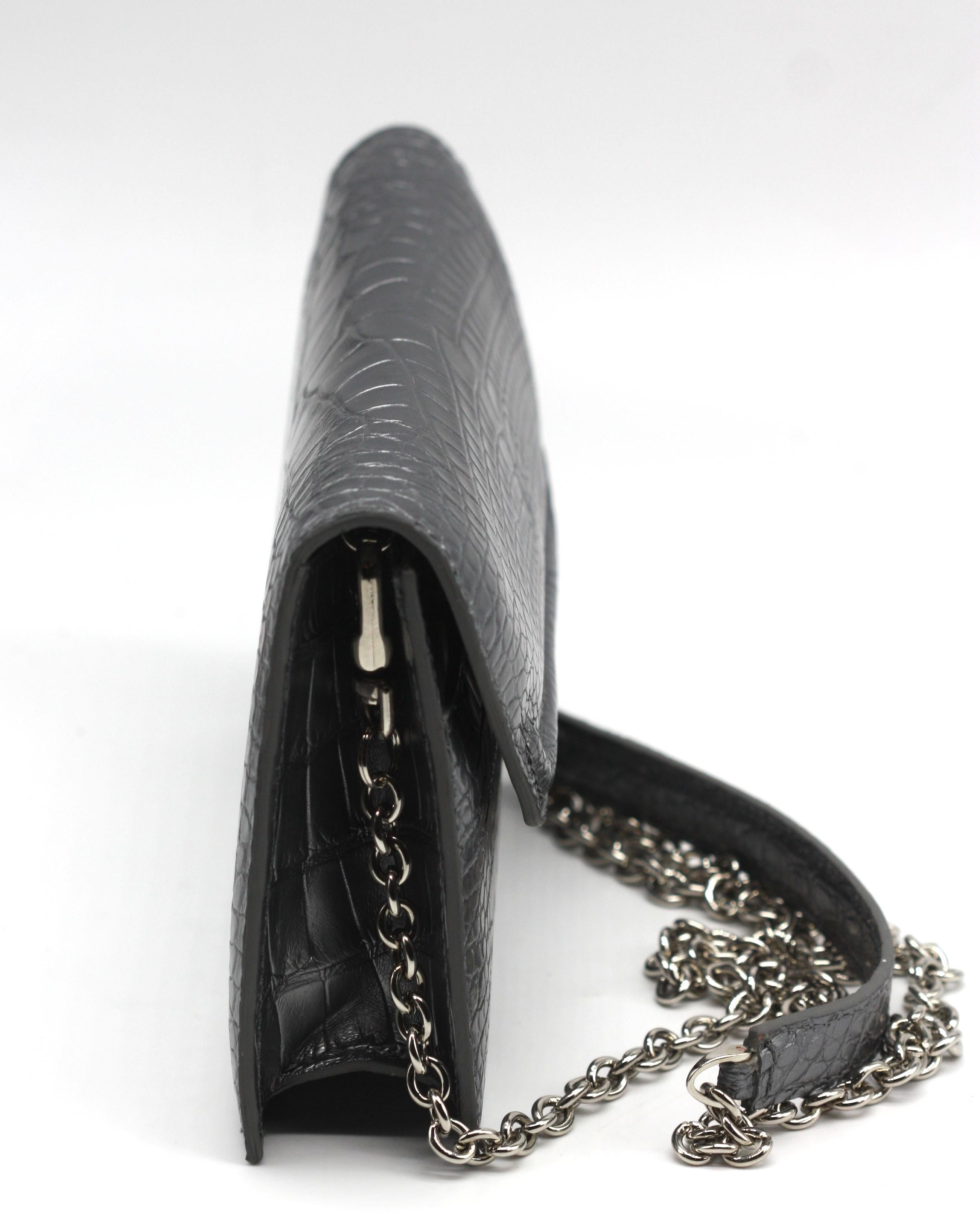 Lana Marks Silbergraue Alligator-Capri-Clutch

Diese raffinierte Capri-Clutch von Lana Marks ist aus silbergrauem Alligatorleder gefertigt und steht für zeitlose Raffinesse. Die rechteckige Silhouette wird durch eine geformte Klappe und einen