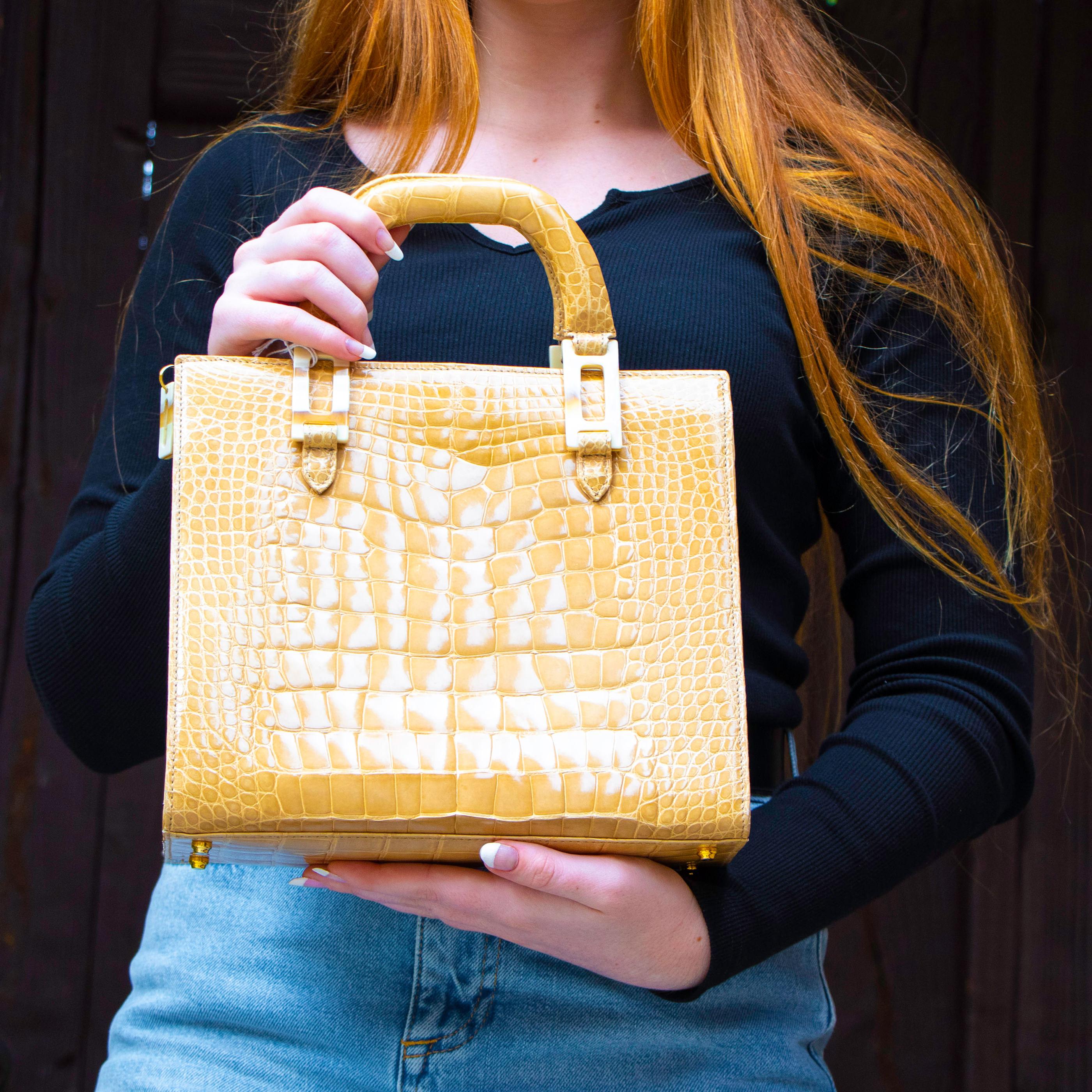 Beautiful tan crocodile handbag with one main pocket with a lucite zip. Within the main pocket there are three side pockets - two side pockets and one zippered section. There is also an external pocket with a magnetic closure. The bag has crocodile