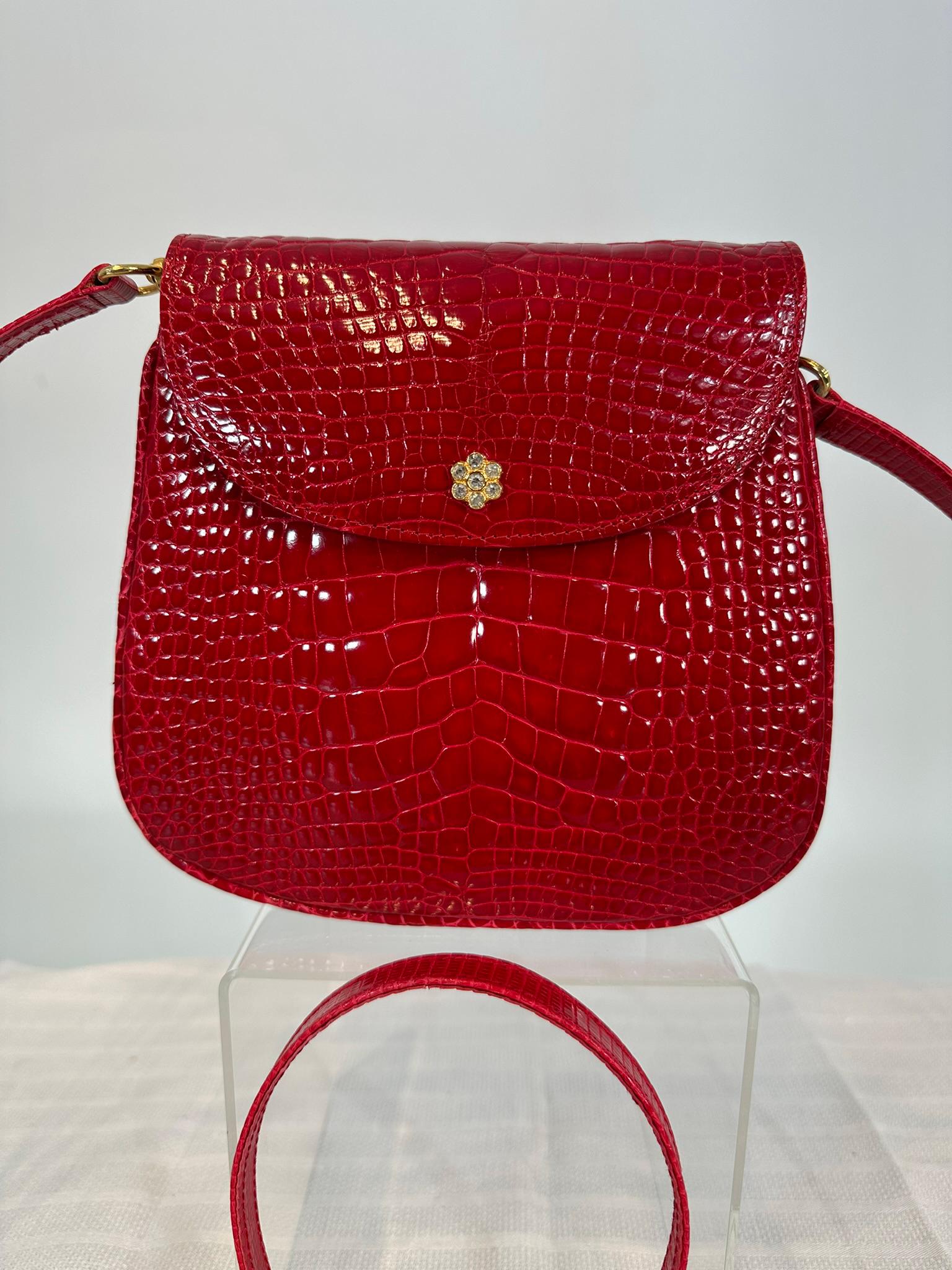 El bolso de mano o bandolera de cocodrilo rojo esmaltado Lana of London puede llevarse como bolso cruzado con cierre de oro y brillantes. Bolso con cierre de solapa y bandolera extraíble herrajes dorados. Forro de cuero negro y rojo. Un único