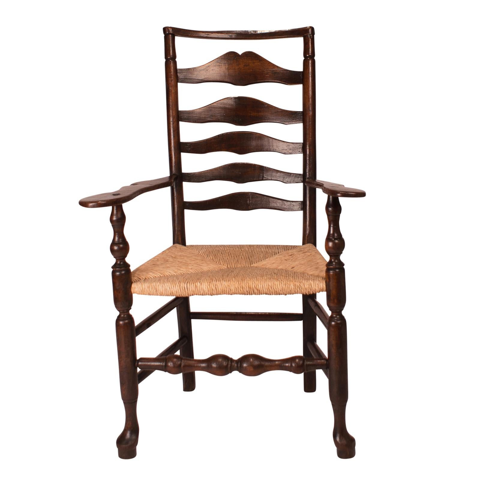 An English oak wavy ladder back Lancashire armchair with a rush seat, circa 1820.