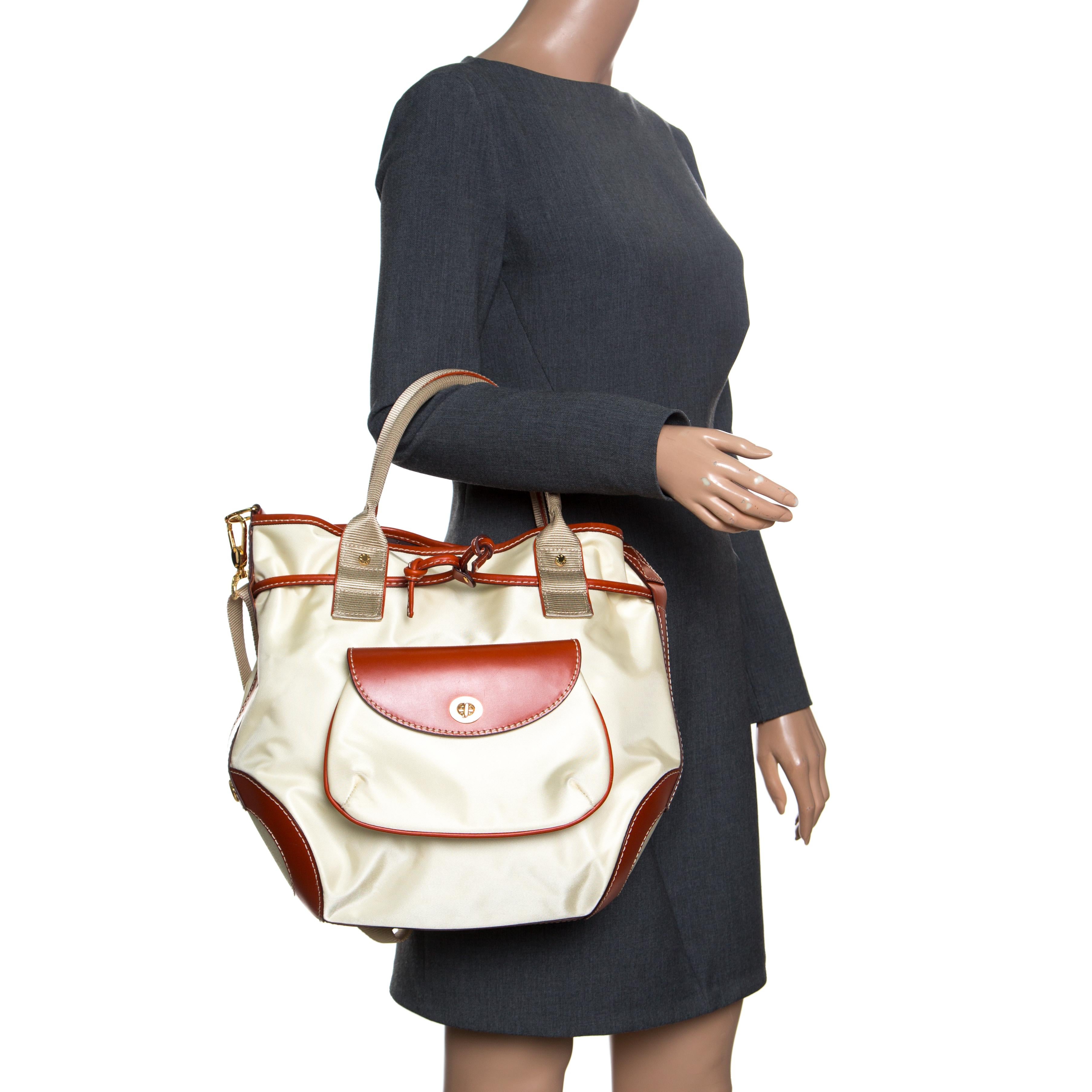 Ce modèle fonctionnel de Lancel est fabriqué en nylon beige et avec des garnitures en cuir marron. Ce sac comporte deux poignées supérieures, une bandoulière amovible et un intérieur doublé de nylon. Fermé par un bouton-pression, l'intérieur abrite