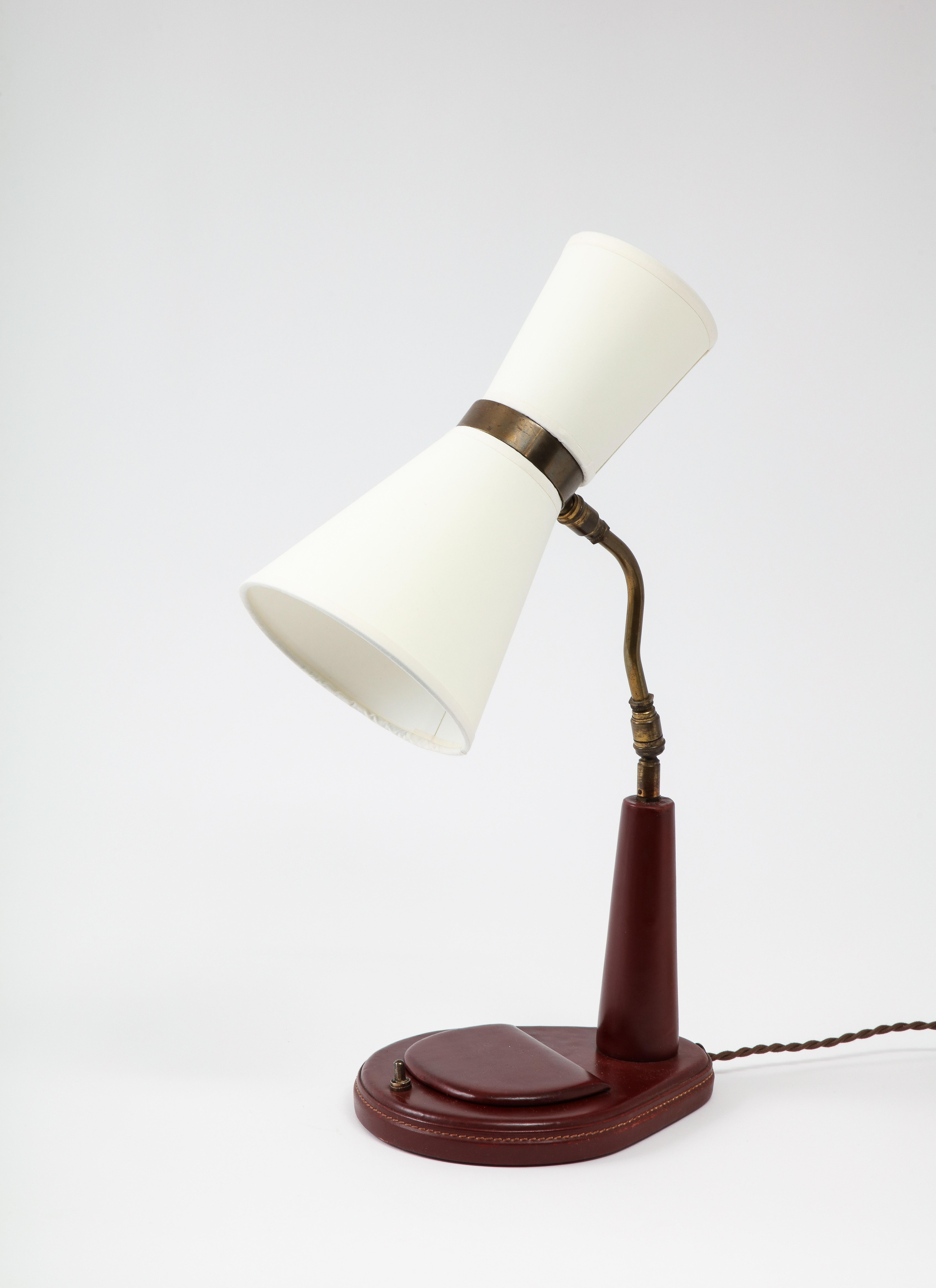 Elegant Lancel desk lamp in burgundy leather; it has a small lidded compartment in the base. The lamp is rewired with a silk cord and period-style plug and comes with custom shades. Candelabra sockets for 60W bulbs