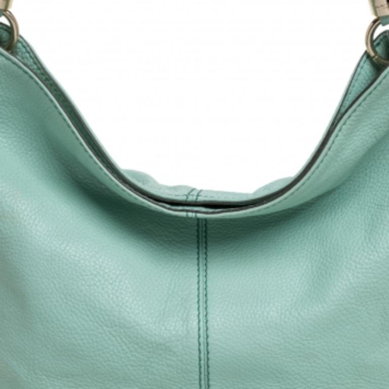 This beautifully-crafted everyday Flair tote from Lancel is spacious enough to hold all that you need through the day. Crafted in mint green leather, this bag features a gold-tone logo detailed charm on the front. With an open-top and two rolled top