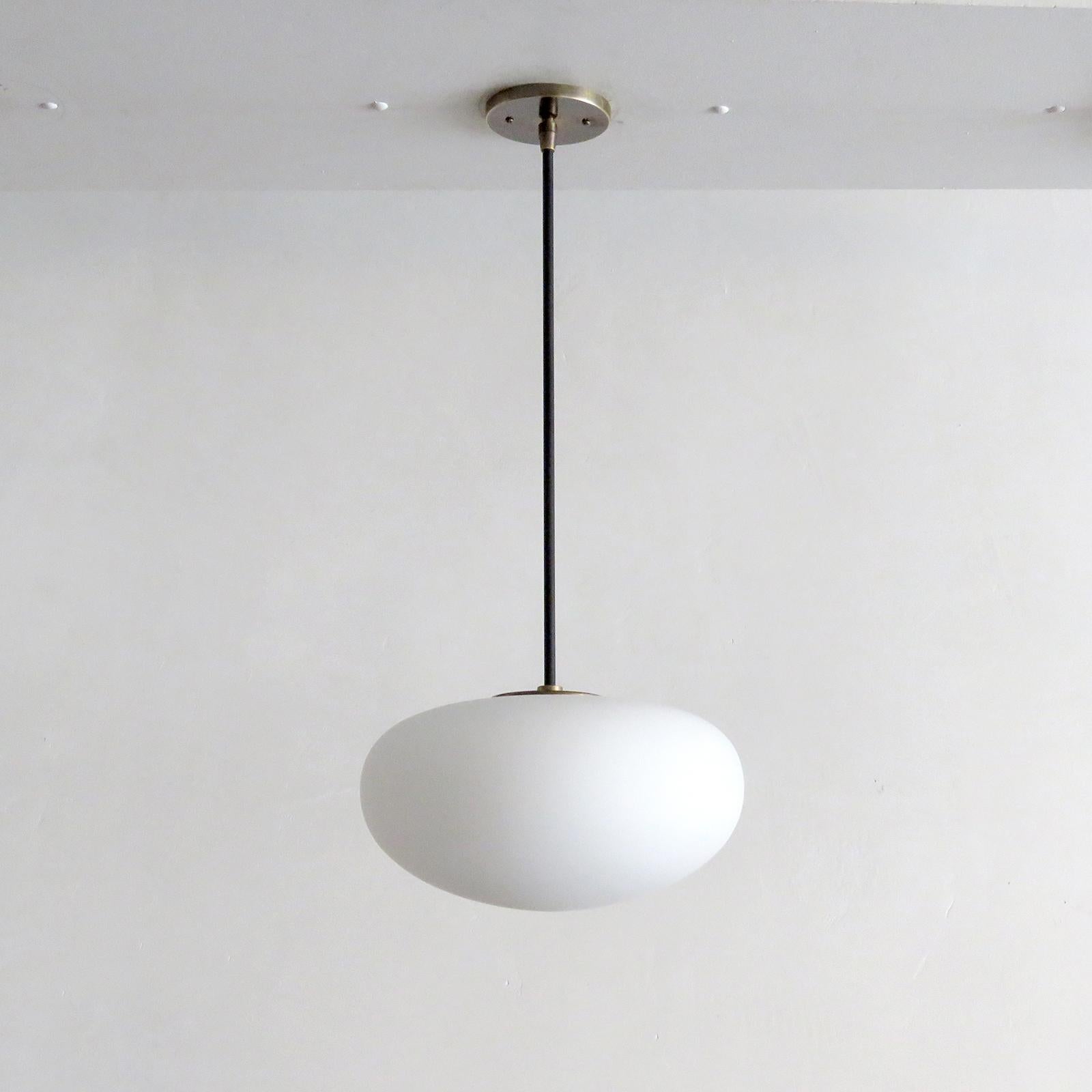 meravigliosa lampada a sospensione a globo singolo di Gallery L7, realizzata e rifinita a mano a Los Angeles in ottone americano con finitura in ottone invecchiato e globo in vetro opalino opaco, misura 30 x 13 pollici, l'altezza del pendente può