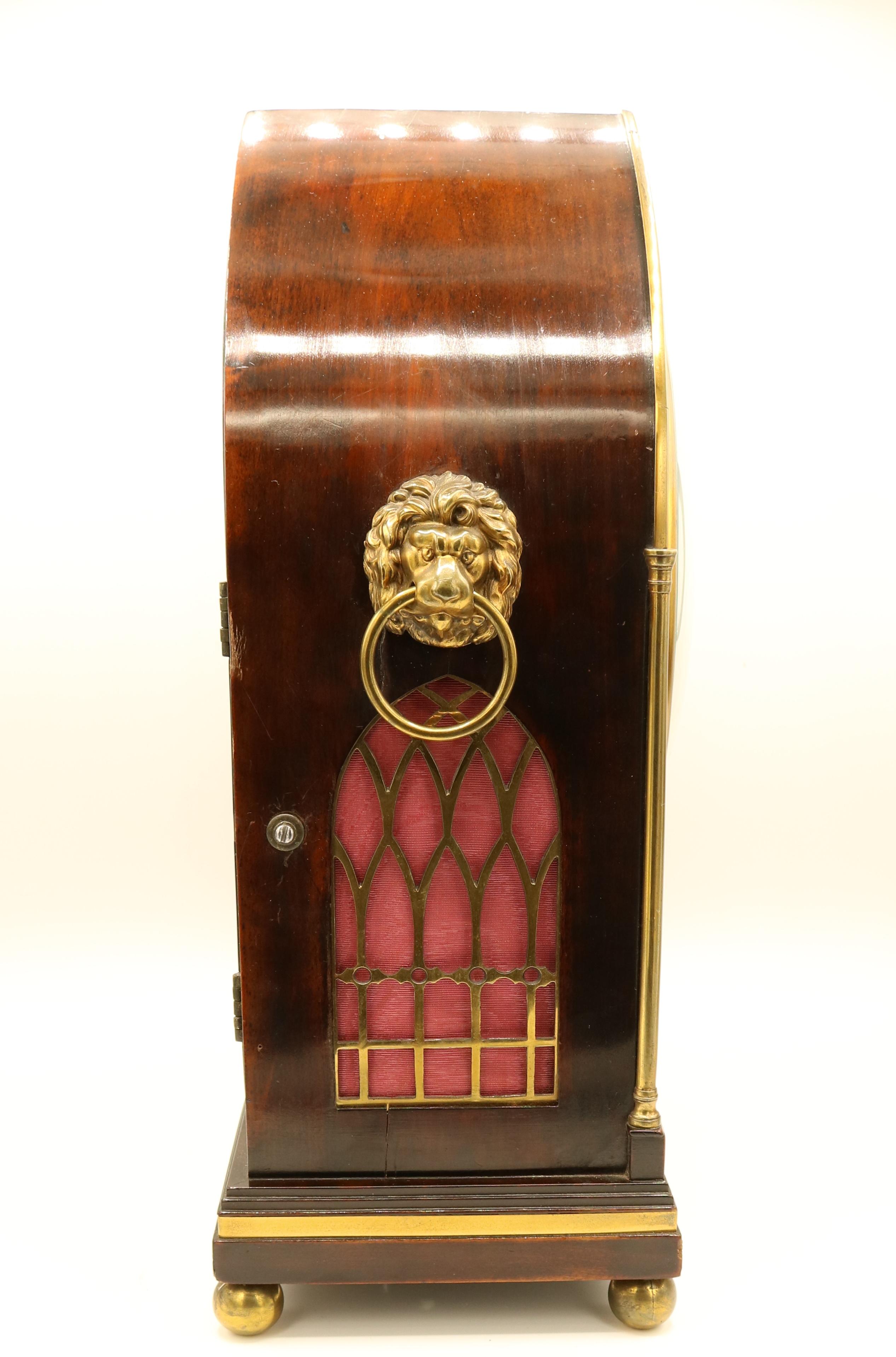 An early 19th century Regency period figured mahogany bracket clock, having 8-day striking movement with painted dial (internal backplate stamped ‘Handley & Moore’) contained in lancet-shaped brass mounted case with column corners and lions head