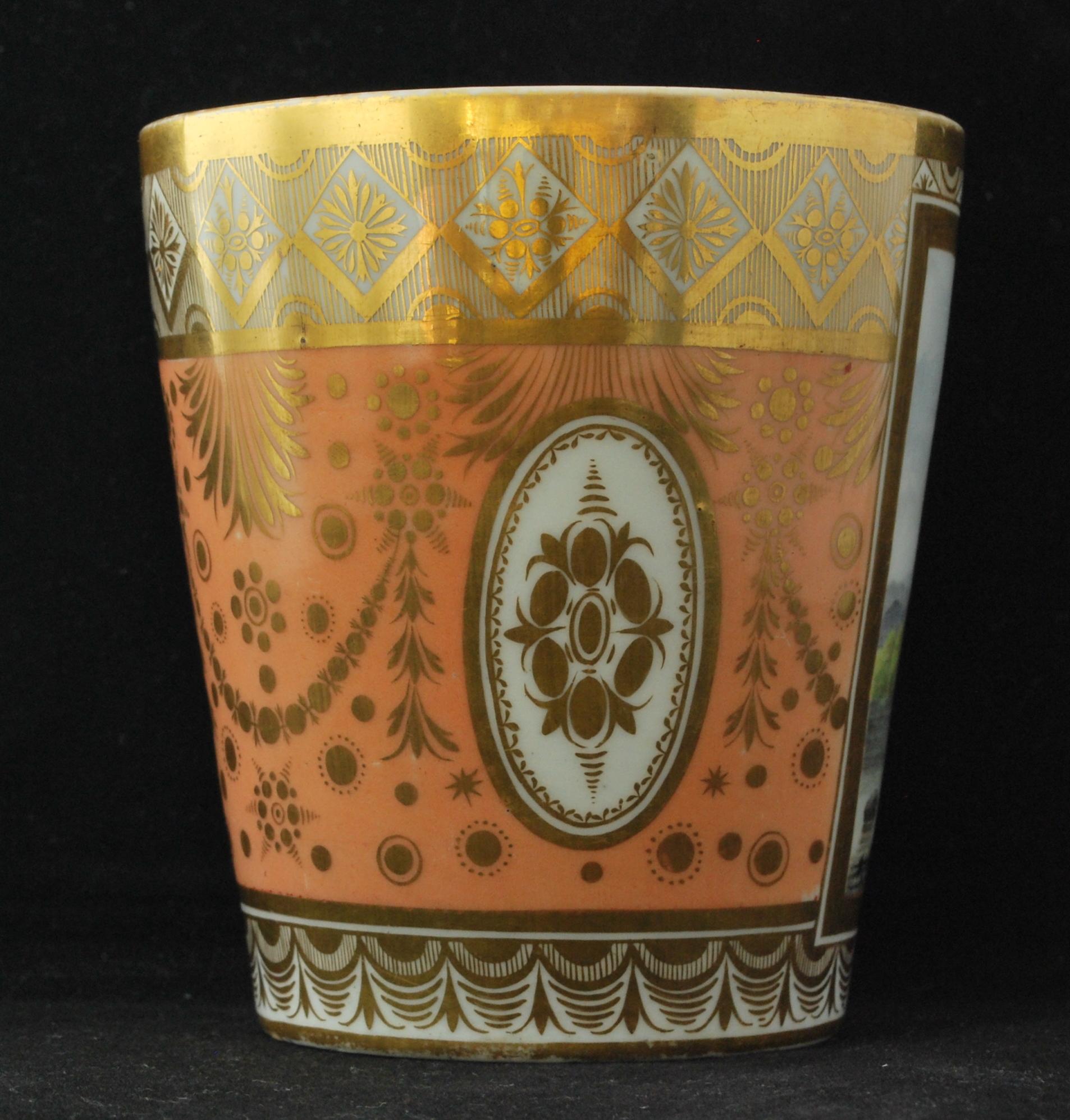 A large beaker with gilt decoration on a salmon-pink ground, revealing a reserve painted with a polychrome landscape.

Provenance: Stockspring Antiques London.