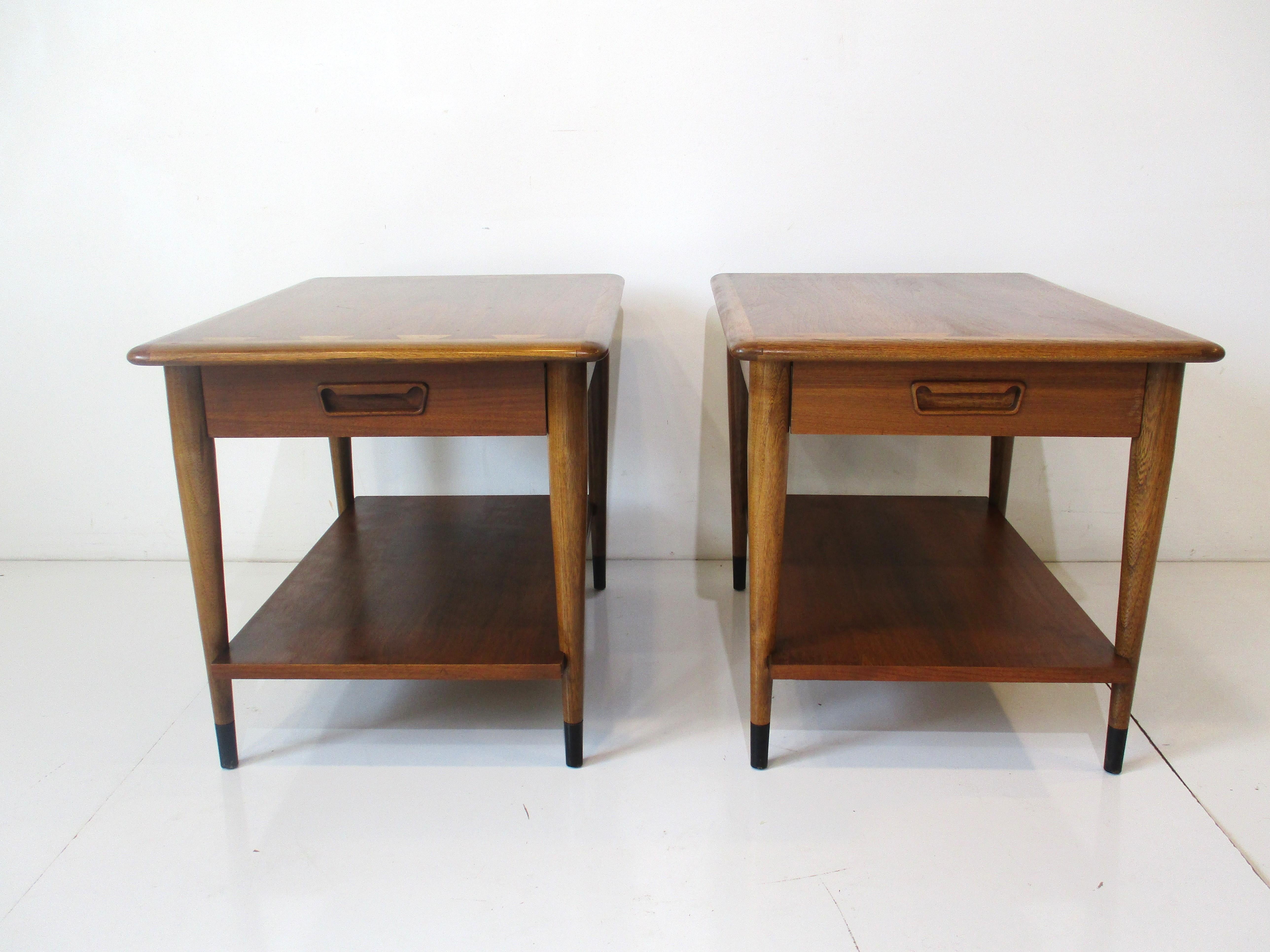 A pair of well crafted end / side tables from the Acclaim collection noted for there contrasting dove tail design. Having a single drawer to each one with a sculptural pull giving the pieces a Danish modern style. Designed by Andre Bus for the Lane