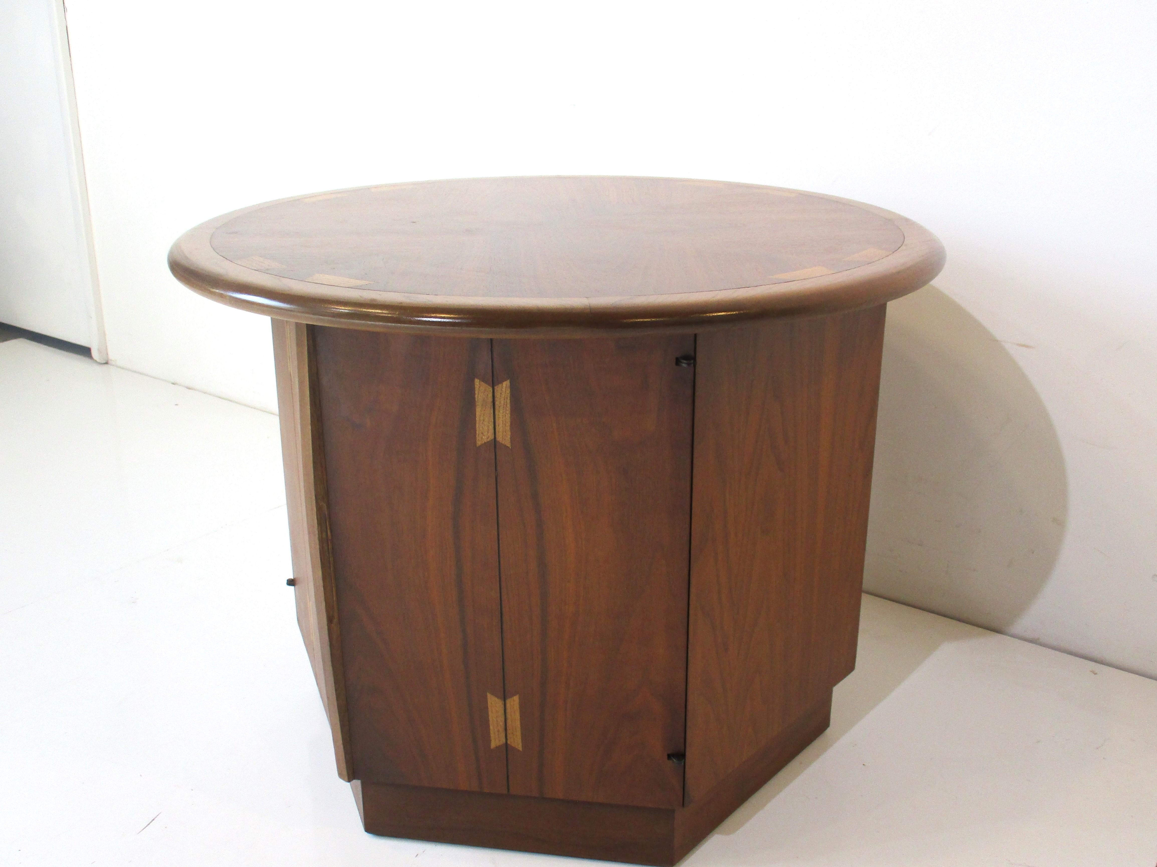 A very well crafted drum side table with wonderful wood graining and to the top book matched walnut with contrasting dovetail detail. The side has a small handle to access the storage area inside with the outside having bowties to the corner edges.