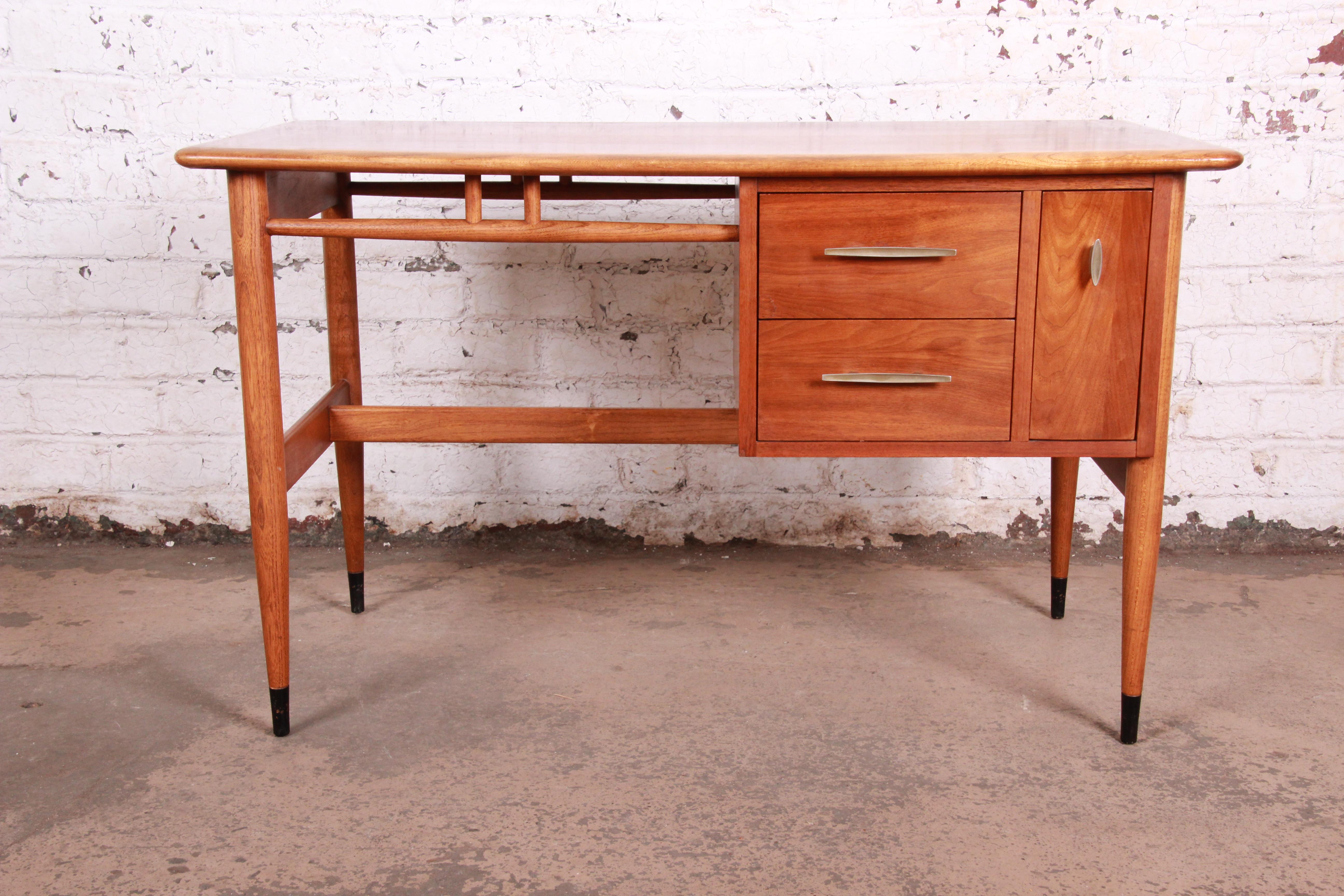 A stunning Mid-Century Modern desk from the acclaim line by Lane Furniture. The desk features gorgeous walnut wood grain with sculpted walnut legs and the iconic ash dovetails on top. It offers good storage, with three deep dovetailed drawers. The