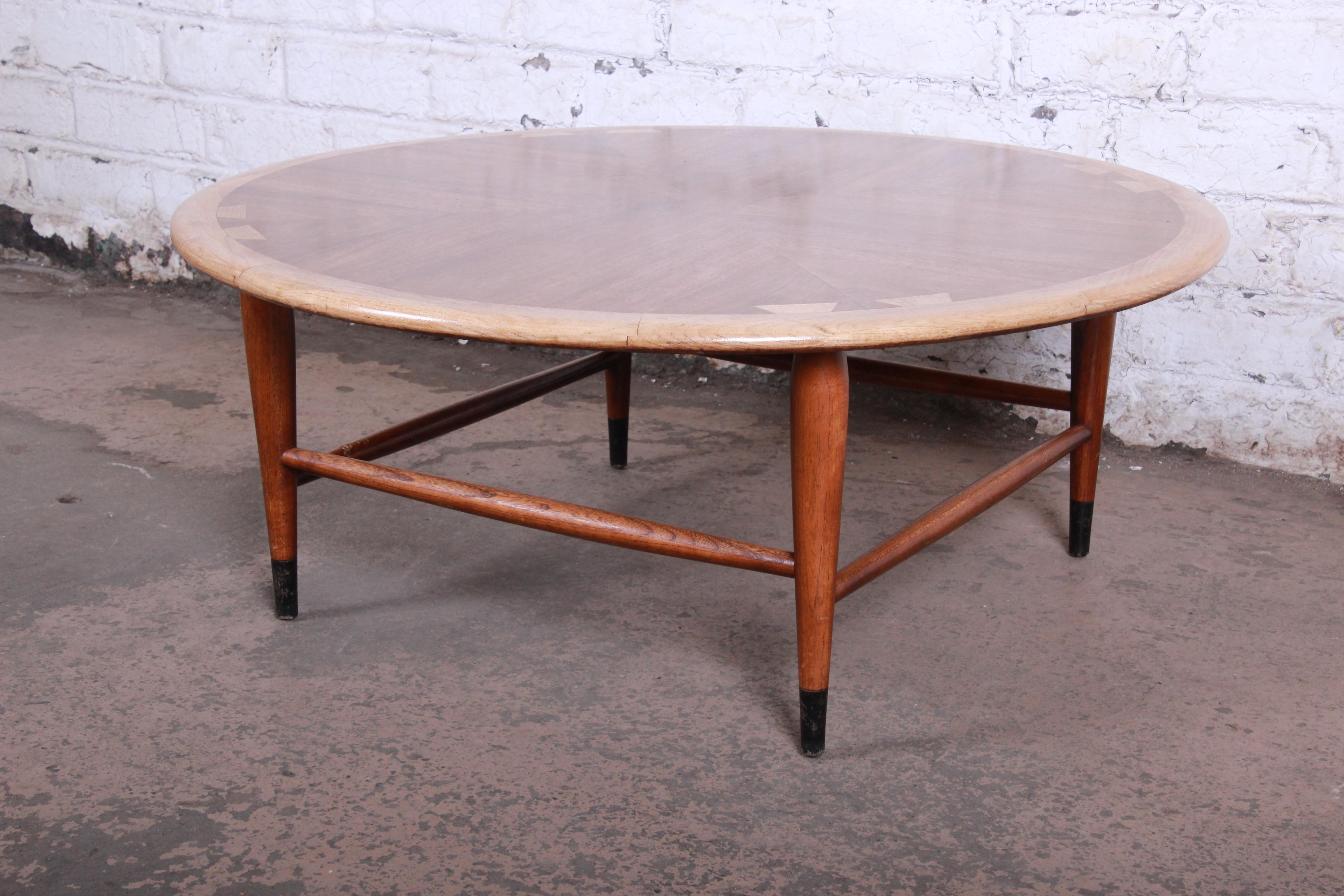 A beautiful Mid-Century Modern round coffee table from the Acclaim line by Lane. The table features gorgeous bookmatched walnut wood grain with the iconic ash dovetails. It has sculpted solid walnut legs and stretchers and ebonized feet. The