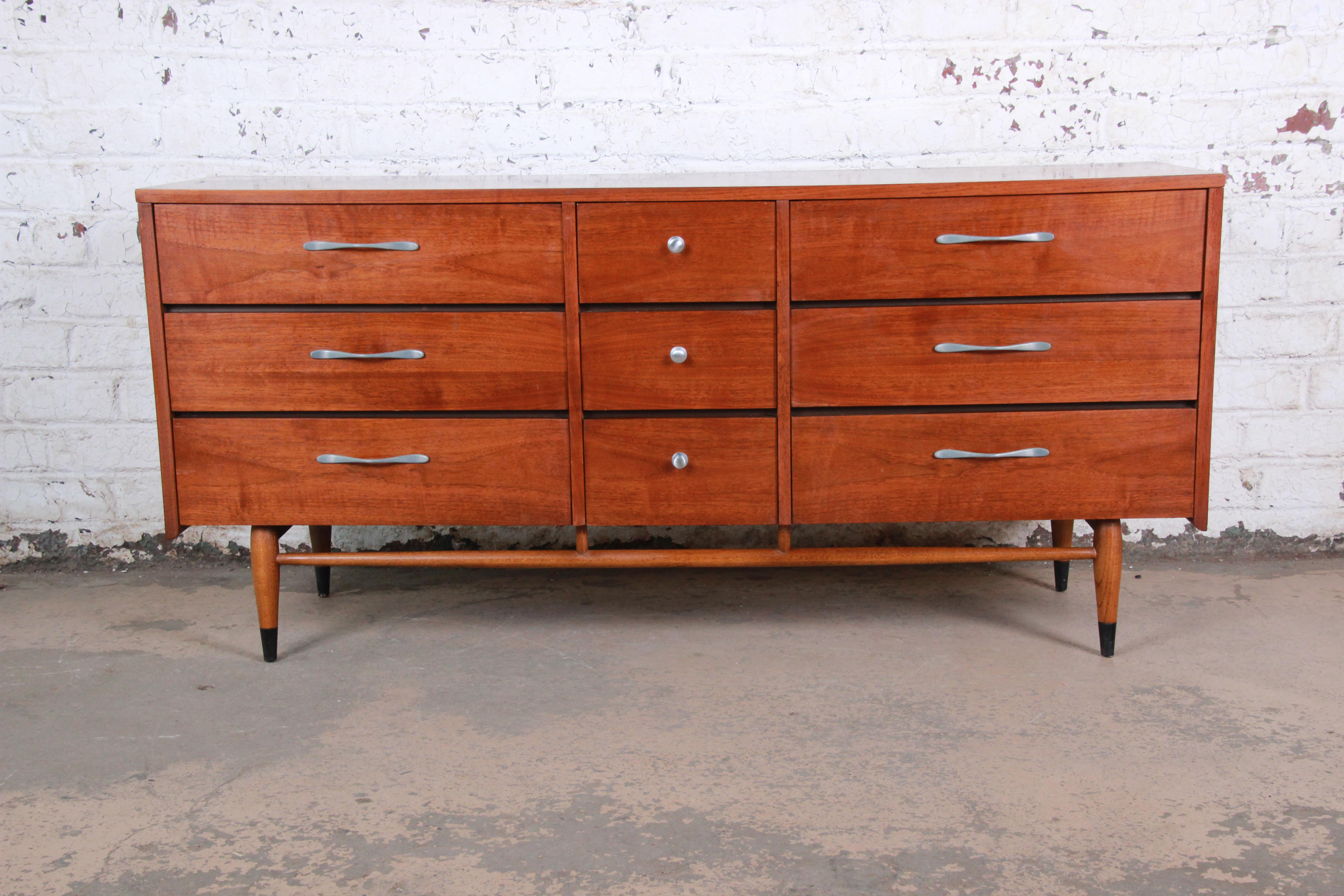 A gorgeous Mid-Century Modern walnut and ash dresser from the Acclaim line by Lane. The dresser features the signature ash dovetails, polished aluminum drawer pulls, and sleek midcentury design. It offers ample storage, with nine dovetailed drawers.