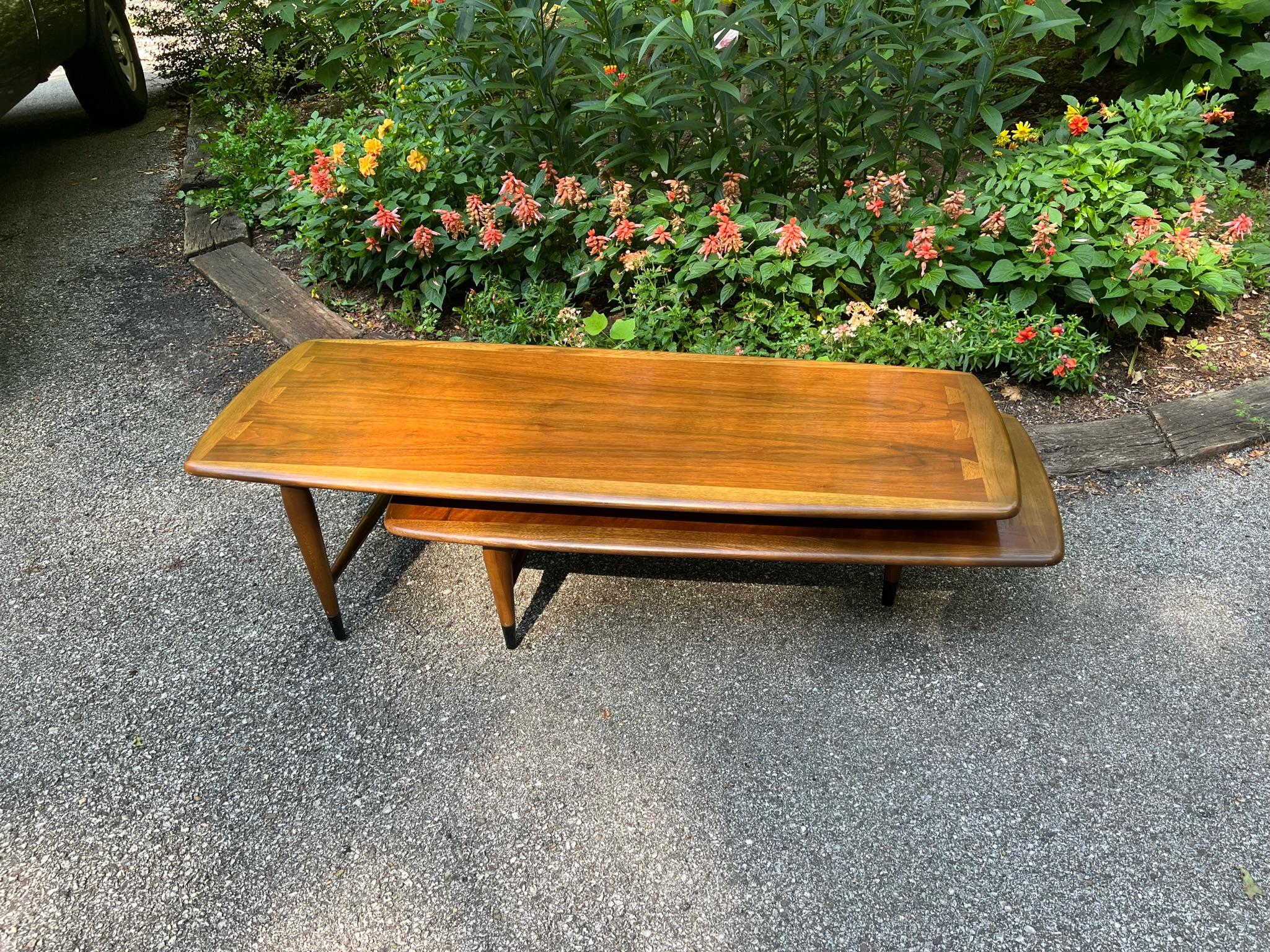 This two piece coffee table (referred to as the Switchblade Table or Boomerang Table) was part of the Acclaim design line by Andre Bus for Lane Furniture introduced in 1958. 

The table has original factory finish and is in like-new condition. The