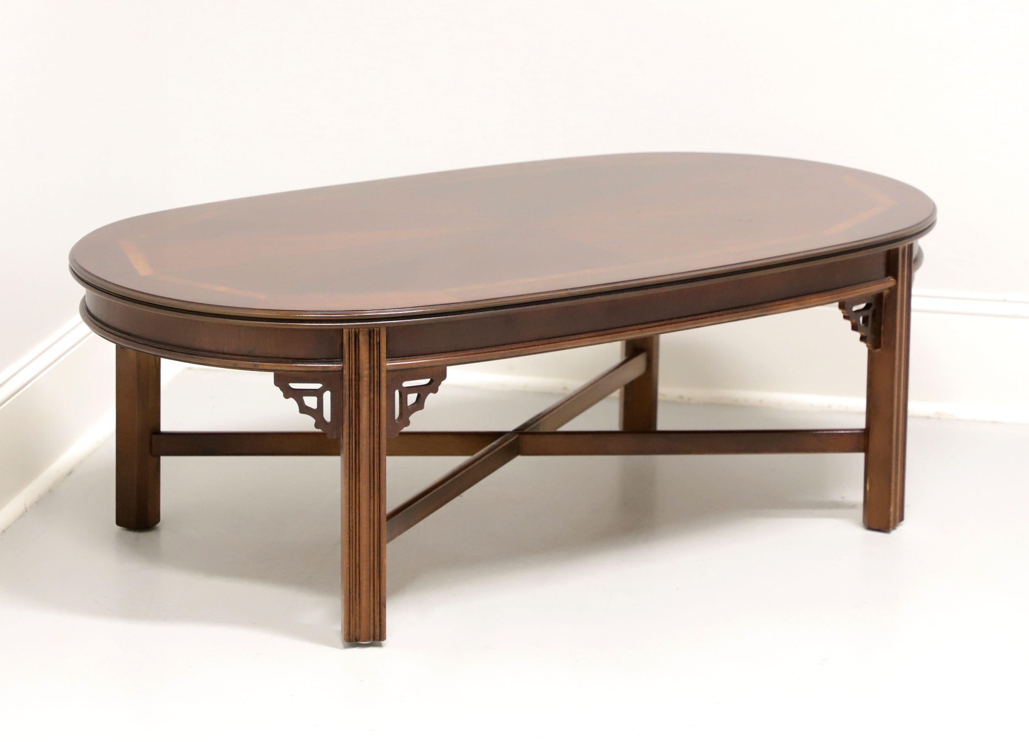 A Chippendale style oval shaped coffee table by Lane Furniture. Mahogany with inlaid & banded top, bevel edge apron, fretwork accents to corner joints, stretchers, and fluted straight legs. Made in Altavista, Virginia, USA, in the late 20th