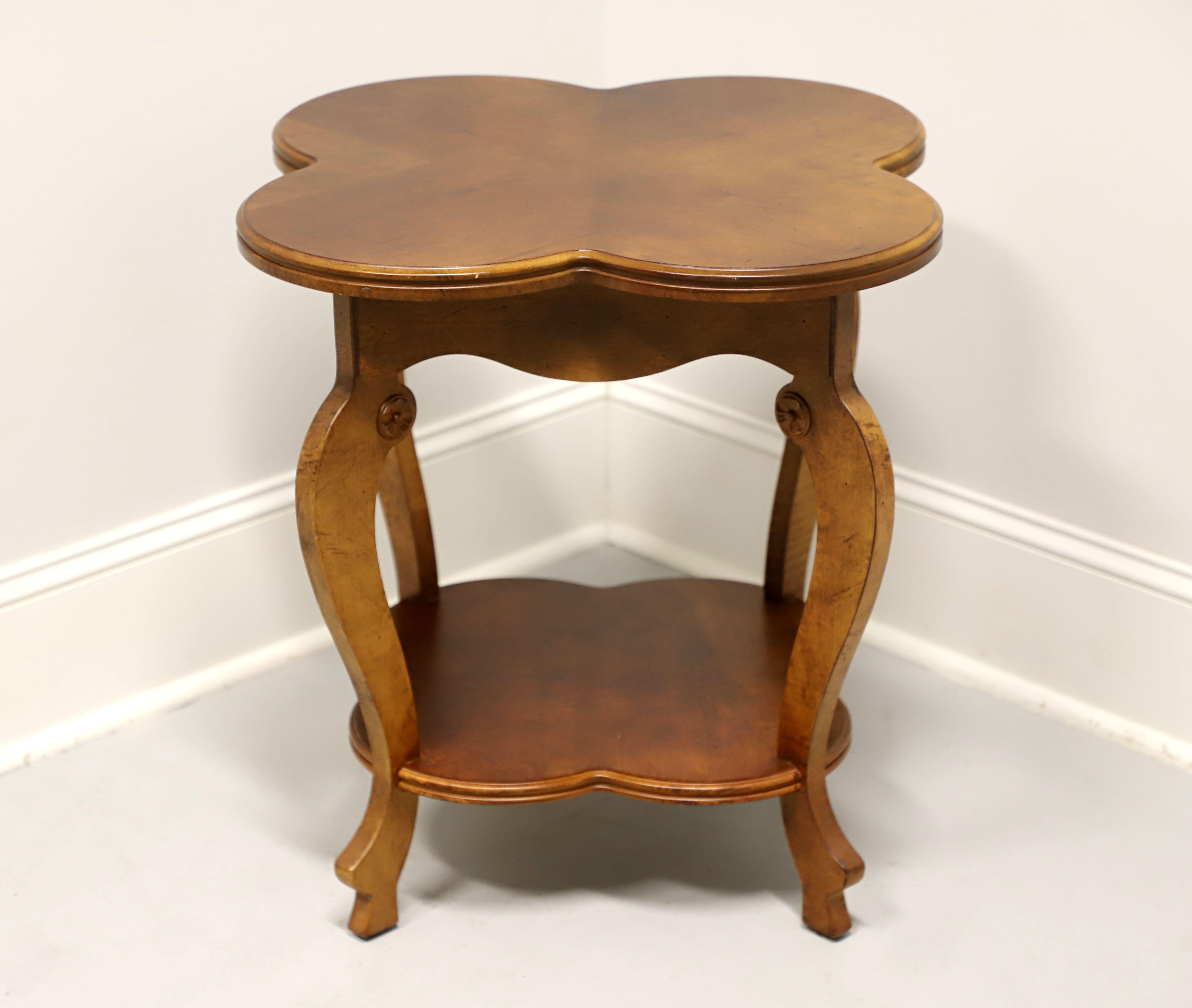An Art Nouveau style accent table by Lane Furniture. Maple with an inlaid four leaf clover shaped top, carved apron, undertier shelf, curved legs with decorative carved medallions under the apron, and carved feet. Made in Altavista, Virginia, USA,
