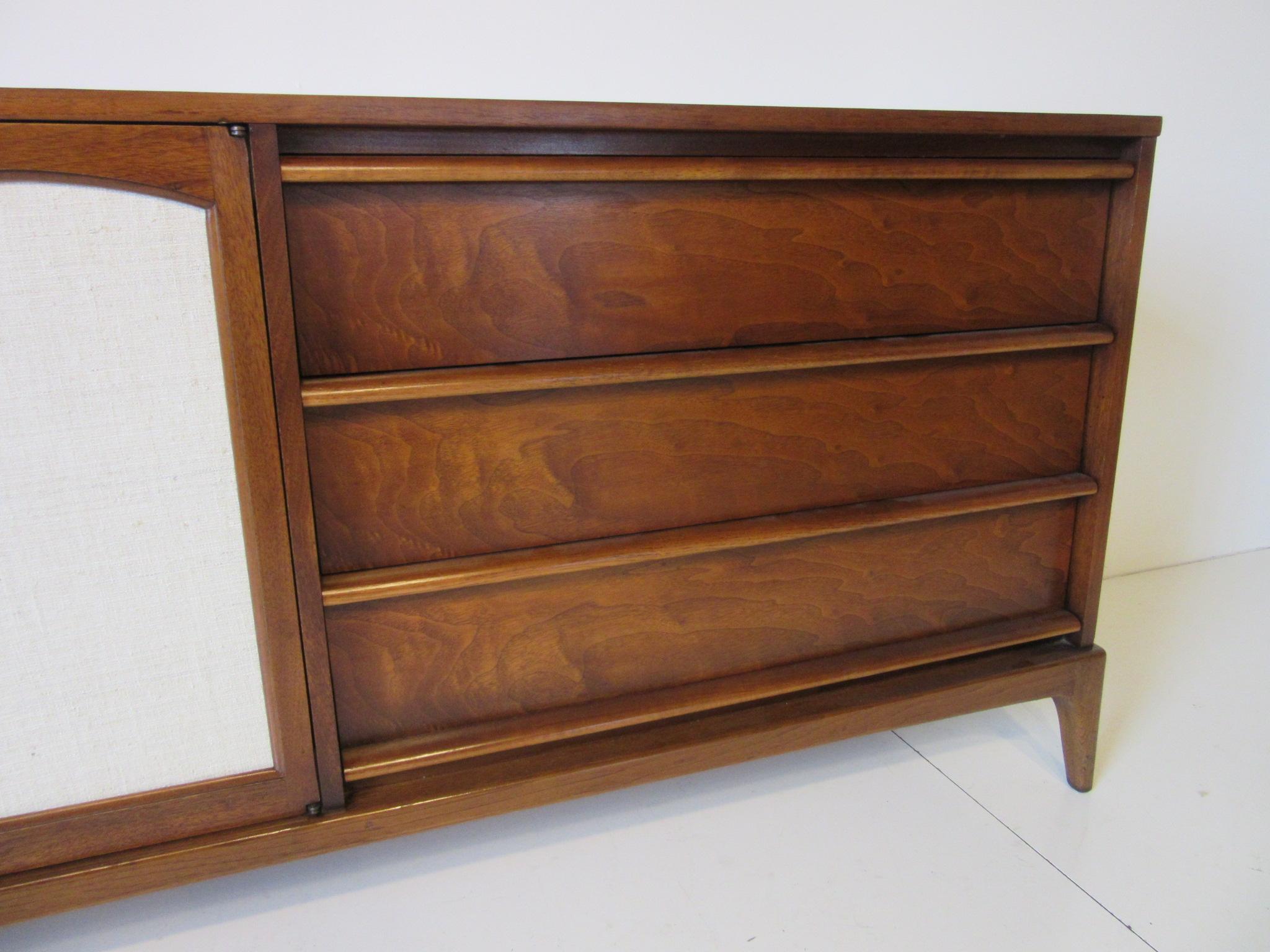 A walnut credenza / server with three drawers and two doors with linen inserts, inside a upper drawer and a adjustable shelve plus storage. This well constructed piece still retains the manufactures branded mark to the inside drawer, Lane Altavista.