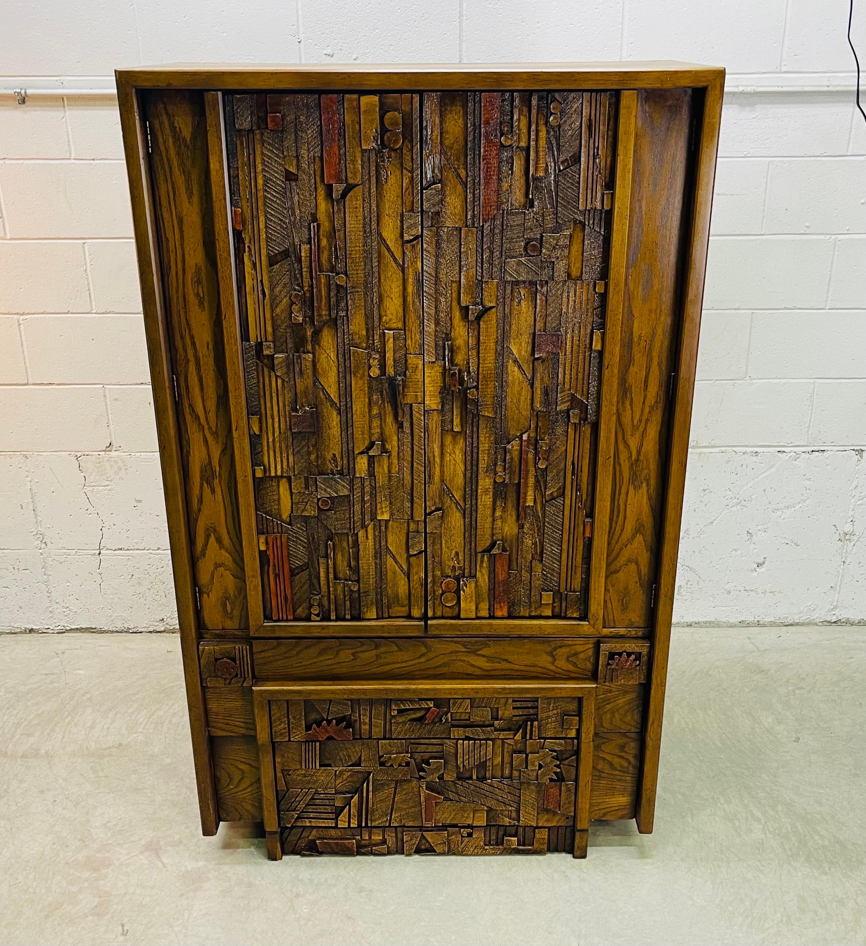 Vintage 1970s brutalist style wood armoire designed by Paul Evans for Lane Furniture Co. There are four large drawers for storage. Two drawers are 4”H and two are 6.25”H. There are also open shelves for additional storage. The exterior has the