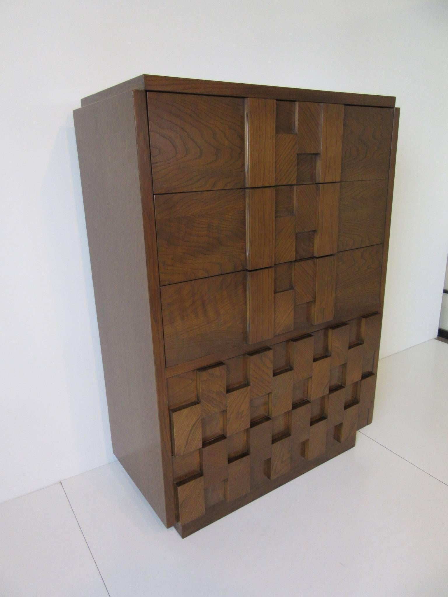 A medium toned Brutalist styled tall dresser or chest with five drawers with block design in the manner of Paul Evans, manufactured by Lane for their Altavista collection.