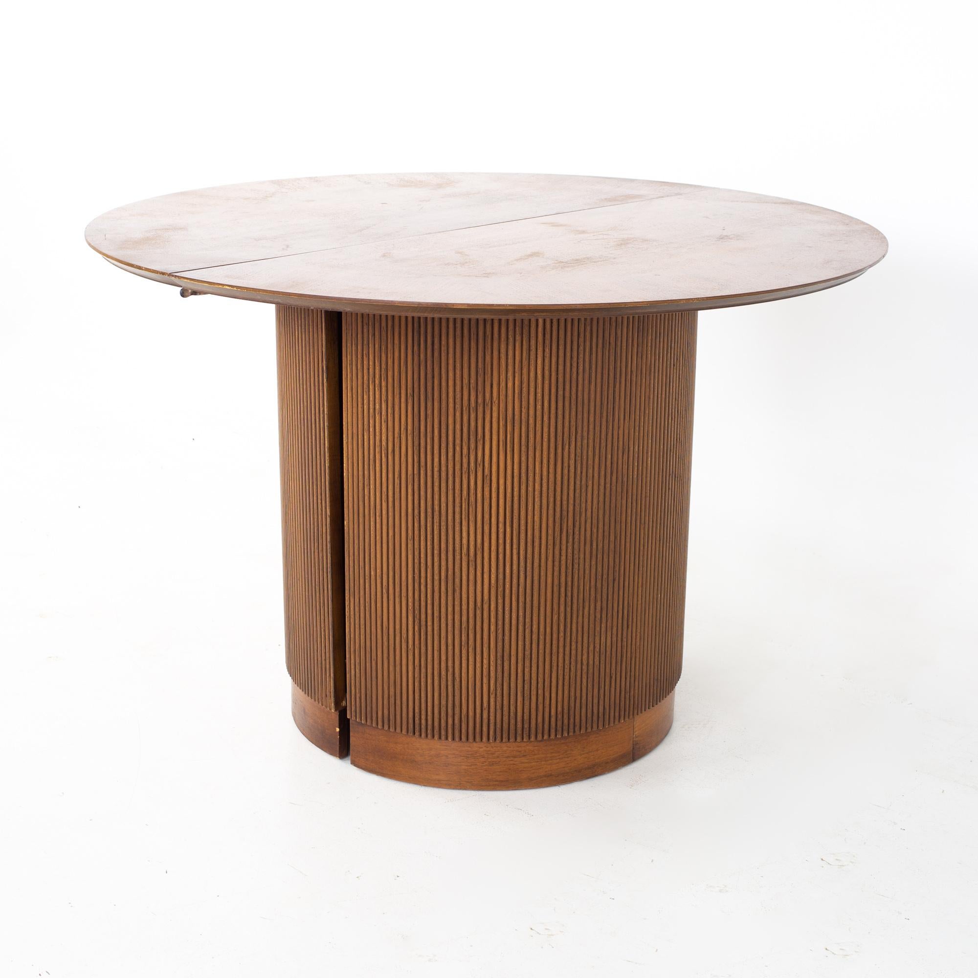 Lane first edition mid century walnut expanding round pedestal dining table.
Table measures: 44.25 wide x 44.25 deep x 29.5 inches high, with a chair clearance of 28.5 inches. Each leaf is 17.5 inches wide, making a maximum table width of 79.25