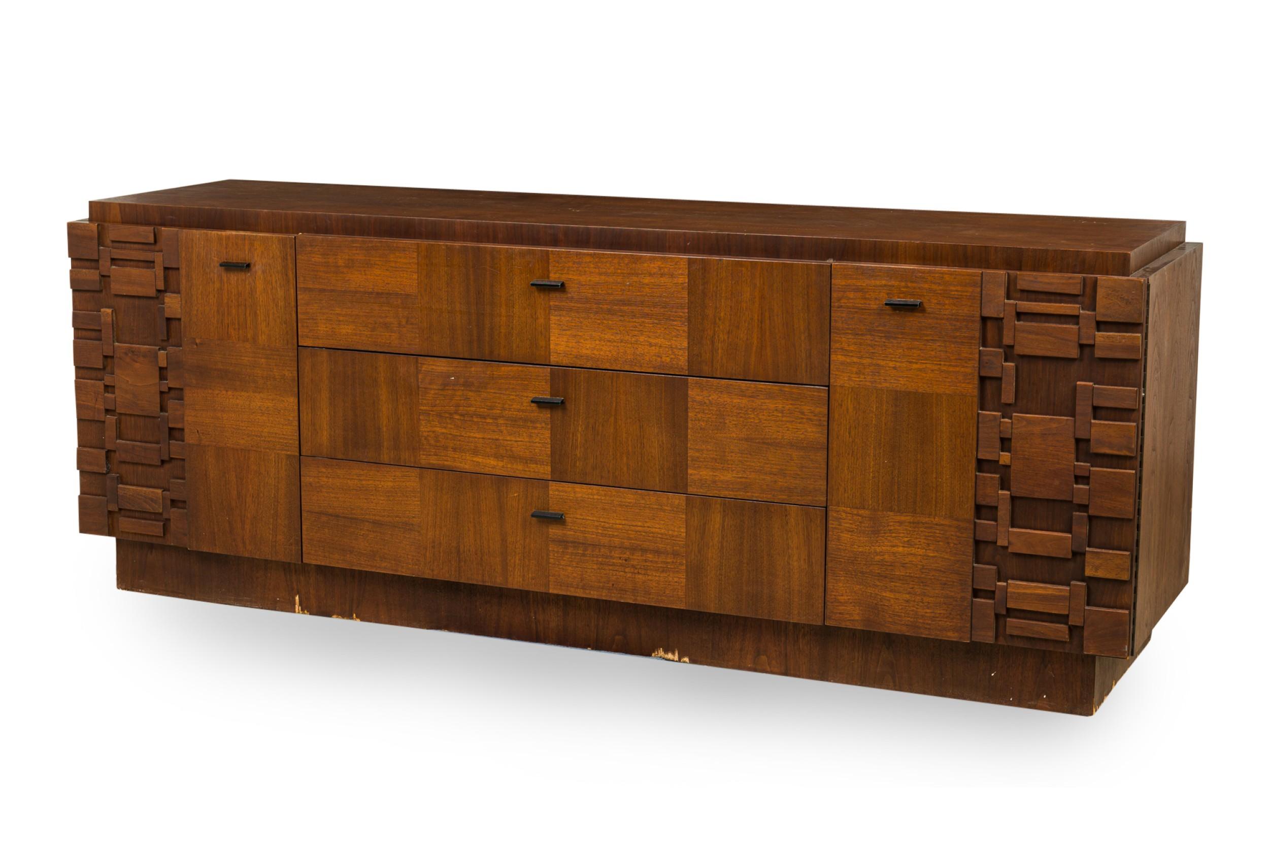 Mid-Century American mahogany lowboy dresser with a contrasting grain veneer checkerboard front surface offset with staccato Brutalist relief corner doors, both opening to reveal 2 hidden columns of pullout drawers plus a central column of 3 equally