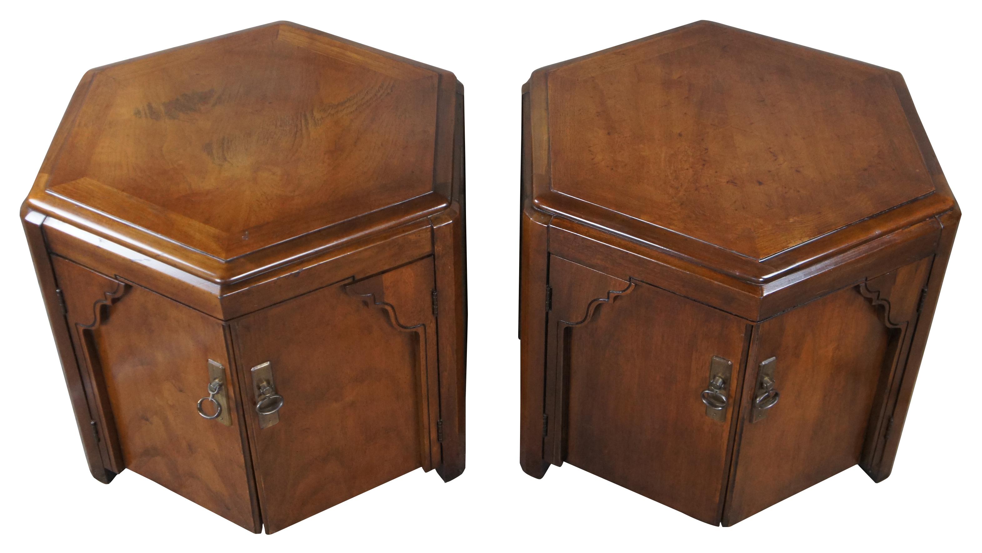 A lovely pair of mid century lane furniture drum tables. Chinoiserie inspired with a hexagonal form made from walnut. Each cabinet opens via brass knocker pulls to storage below.
  