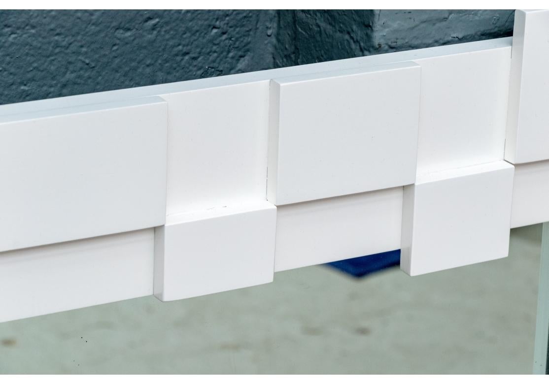 A pair of Mid Century wall mirrors in professionally white spray finished wood. They have a distinctive top frieze with a double row of alternating projecting rectangles. The base has a projecting rectangle within the ends. 

Dimensions: 44