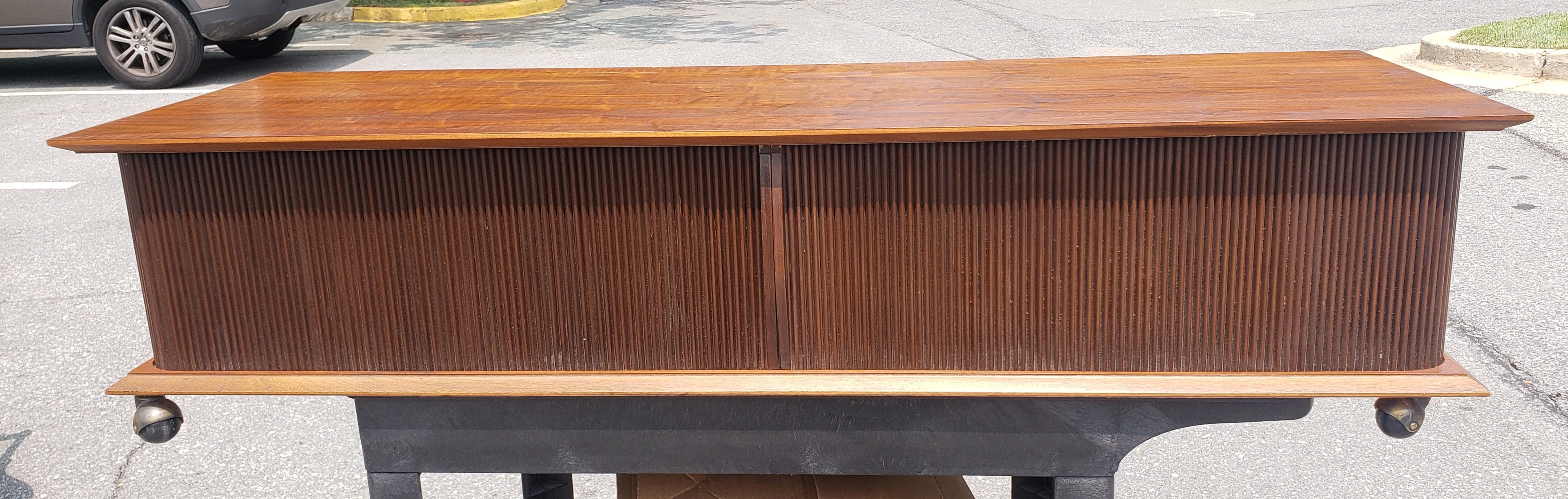 A rare Lane Mid-Century Modern Style Teak And Tambour Door Base Rolling Coffee Table in great vintage condition. 
The Two Sliding tambour doors will close completely to leave the oposite side patially open to reveal the storage compartments. 