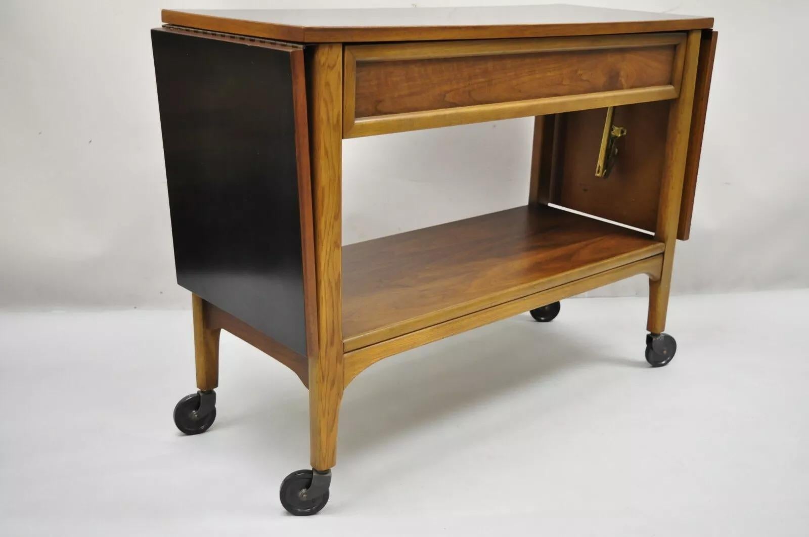Carrito de bar rodante Lane Mid Century Modern Walnut One Drawer Drop Leaf. Con laterales abatibles, ruedas giratorias, encimera laminada negra, 1 cajón de cola de milano, parte trasera acabada, líneas modernistas limpias y artesanía americana de