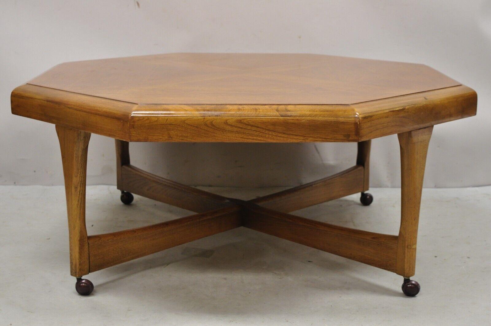 Lane Mid Century Modern Walnut Octagonal Stretcher Base coffee table. Item features a cross stretcher base, rolling casters, octagonal top, beautiful wood grain, original stamp, tapered legs, clean modernist lines. Age: Mid 20th