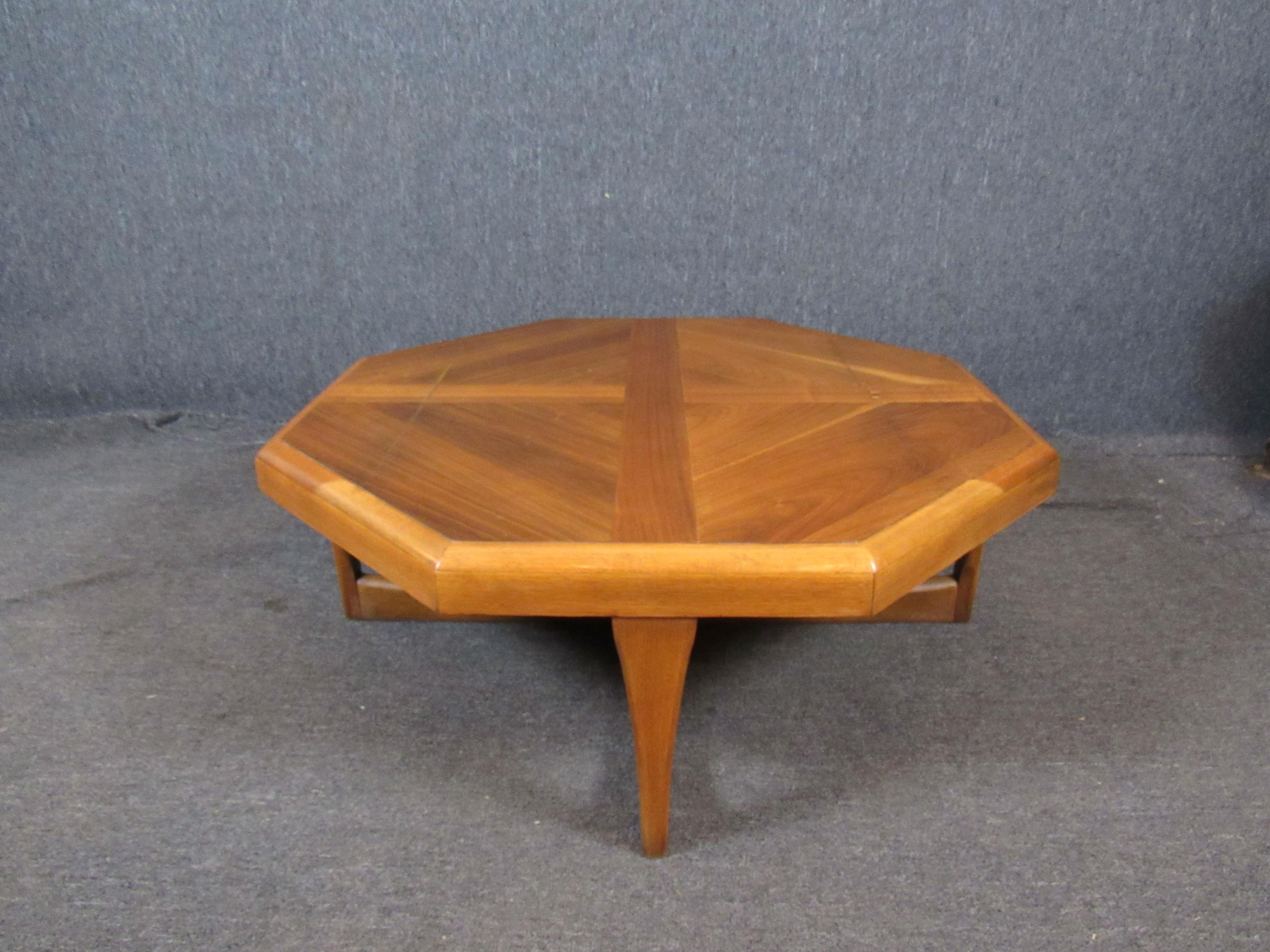 This coffee table is sure to make people stop and stare! A large octagonal table top features contrasting veneers that show off an exceptional natural grain. Crossed sled legs help lend unparalleled stability. A classic mid-century design from the