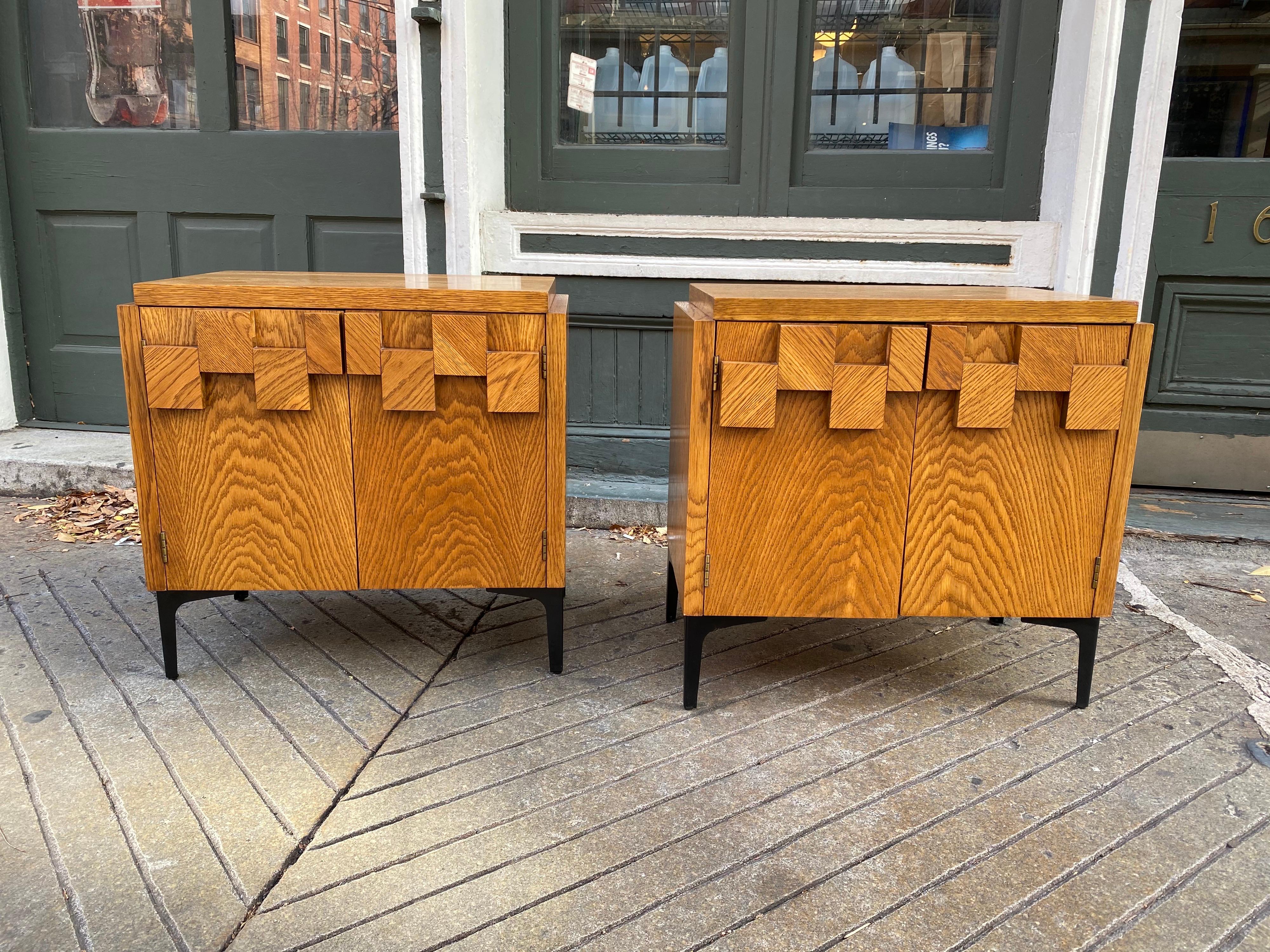 Nice matched pair of Lane end tables or nightstands in their original finish. Cubist feel to the top of each door. Rich grain throughout. Black iron legs give a nice juxtaposition to the wood cabinets.