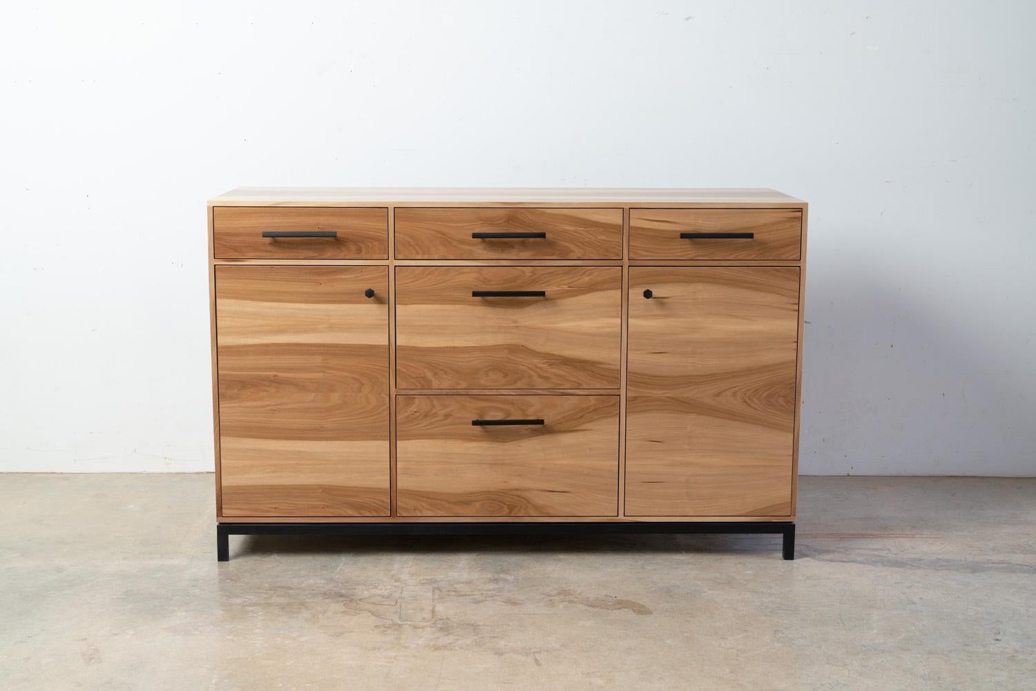 The Lanett credenza is a Modern Credenza in Sweet Gum (Satin Walnut) with Black Patina Steel Base. It is handcrafted and unique in every way. The elegance of this modern style credenza strikes from the first moment with intricate veneer work