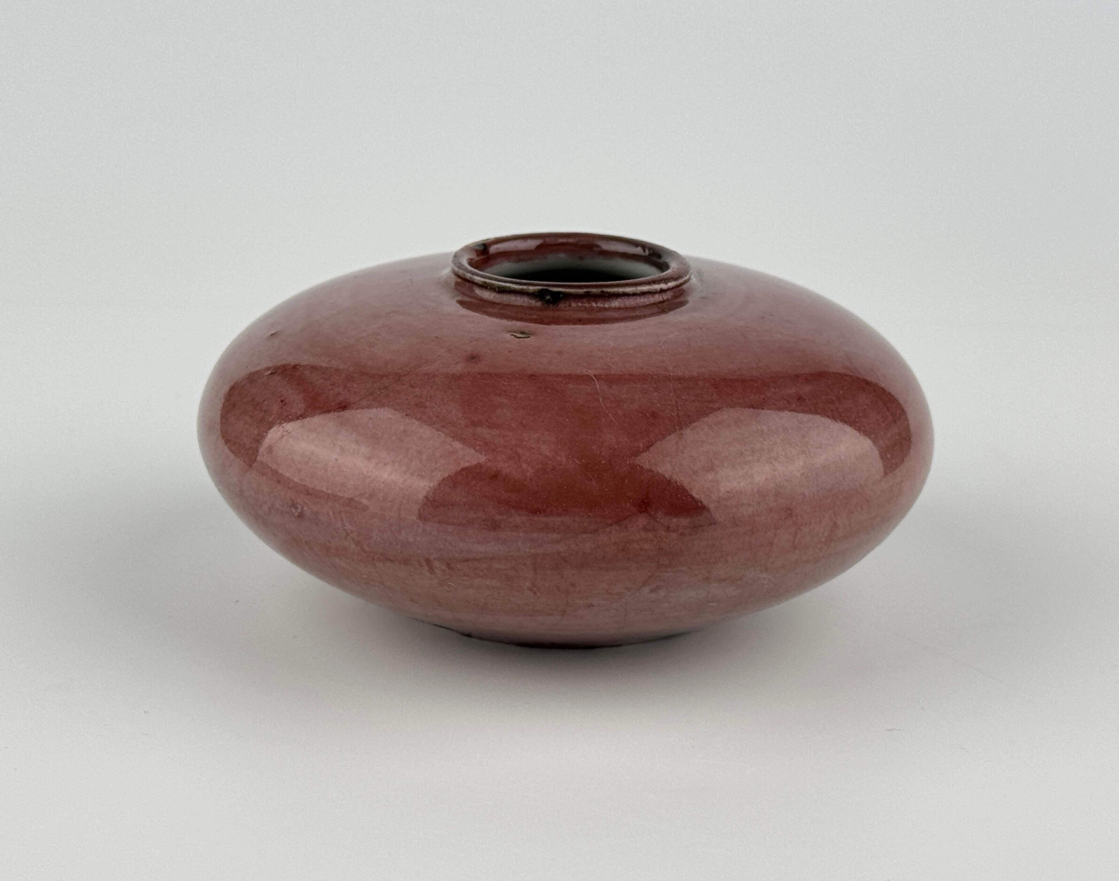 Questo pezzo di ceramica presenta una forma bassa e arrotondata con una bocca stretta, esemplificando una semplicità e un equilibrio raffinati. La superficie è ricoperta da una ricca e profonda glassa cremisi, probabilmente derivata dall'ossido di
