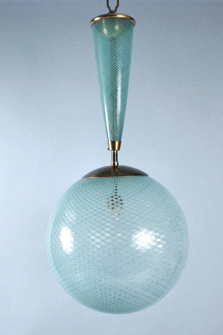 Handblown glass sphere and conical shaft with green, ribbon-like filigree. 
Venini blue catalog model #138.