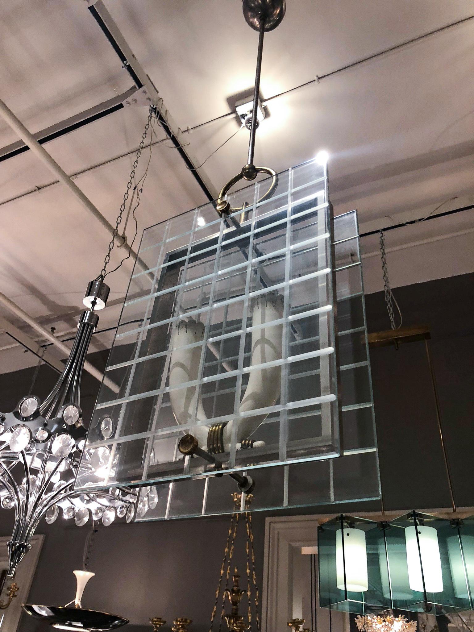 Two glass panes etched with a grid motif, enclosing two upturned lights in a rectangular nickel-finished frame with brass trim, suspended from a single rod.
Measures: Lantern body height 16-1/2”. 

OUR REFERENCE N8415
